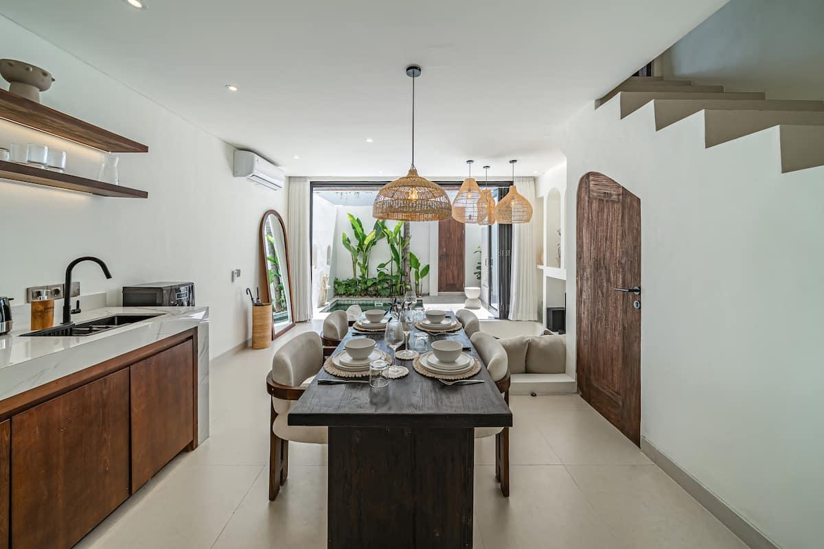 Dark timber kitchen and a dining table for six under a rattan dome pendant, staircase behind