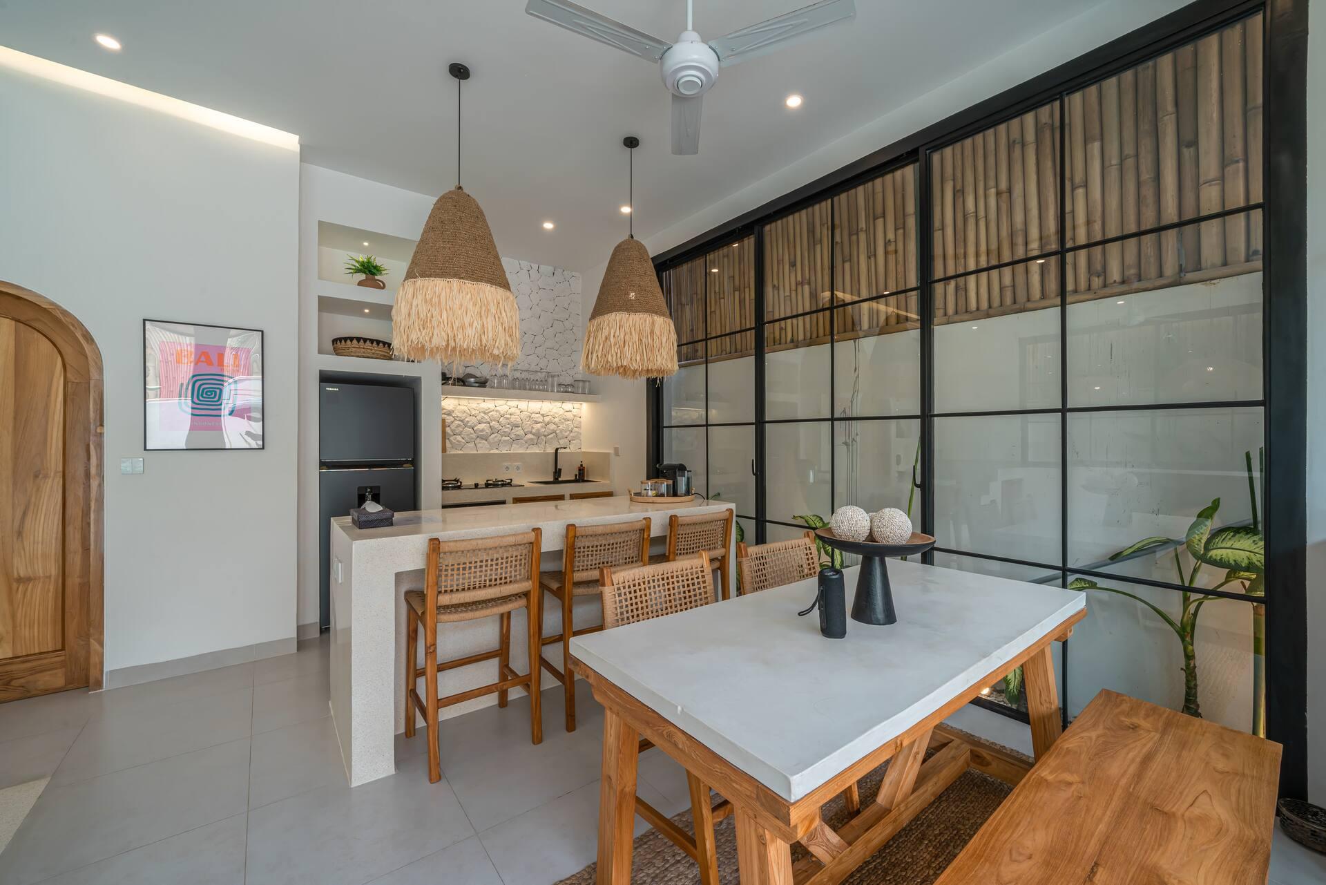 Kitchen and dining table under woven rattan pendants at Villa Sagu