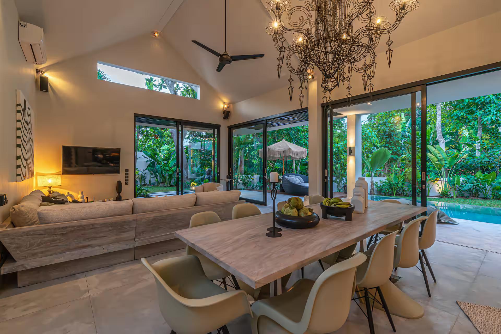 Dining table for ten under a beaded crystal chandelier at Villa Prana, doors open to the pool
