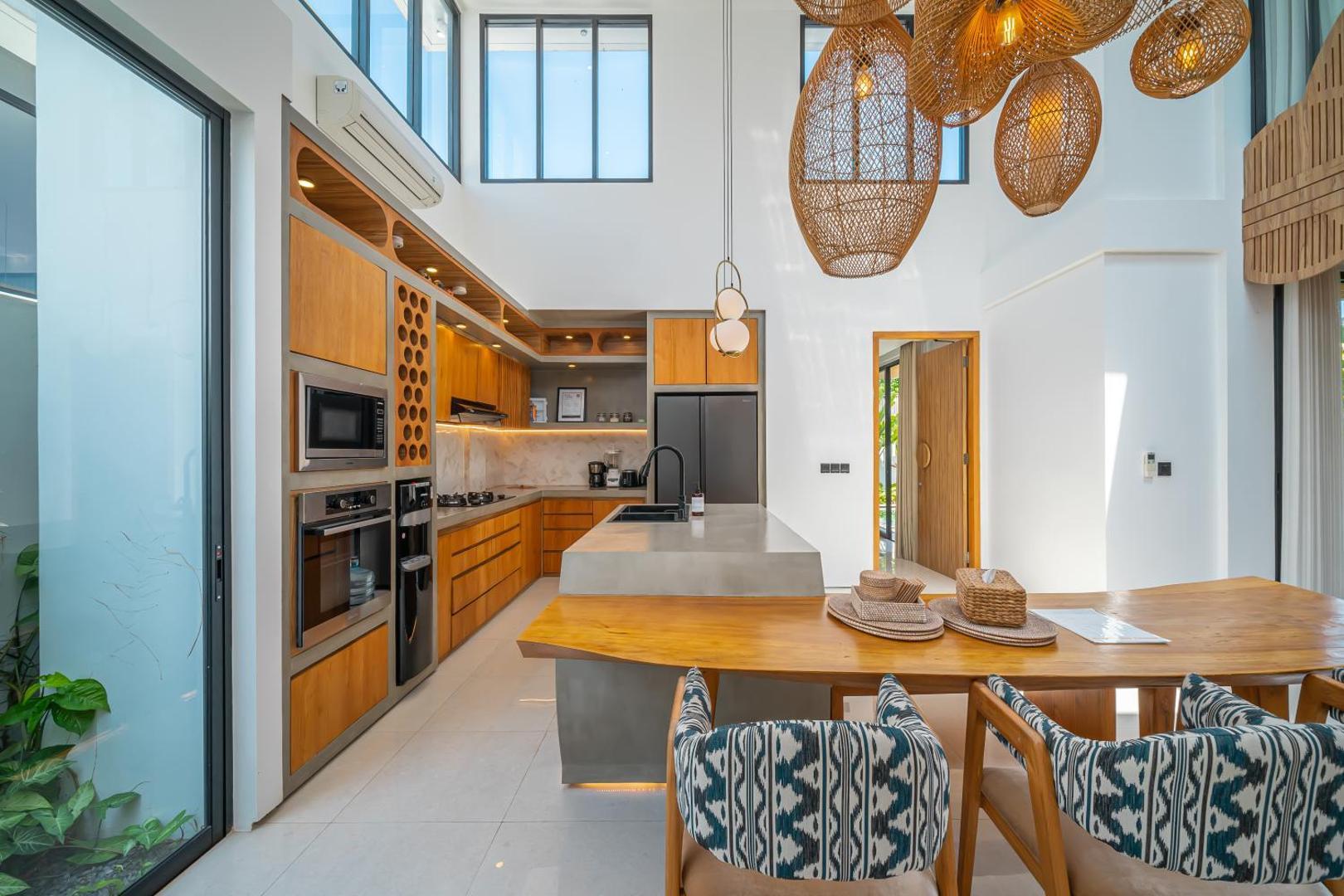 Timber kitchen with a pale stone island and a dining table under woven rattan pendants