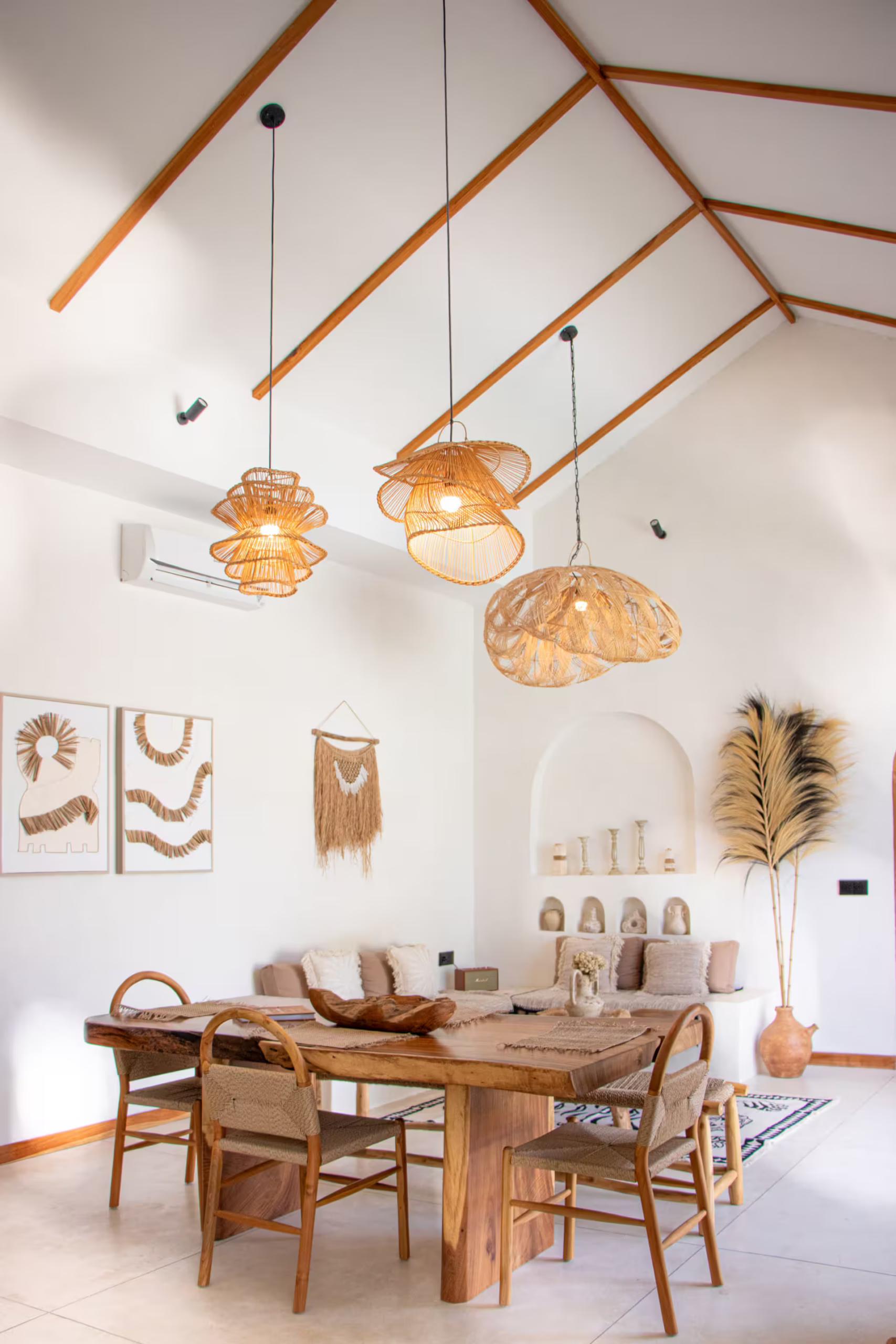 Dining table and cane chairs under woven rattan pendants and exposed timber rafters