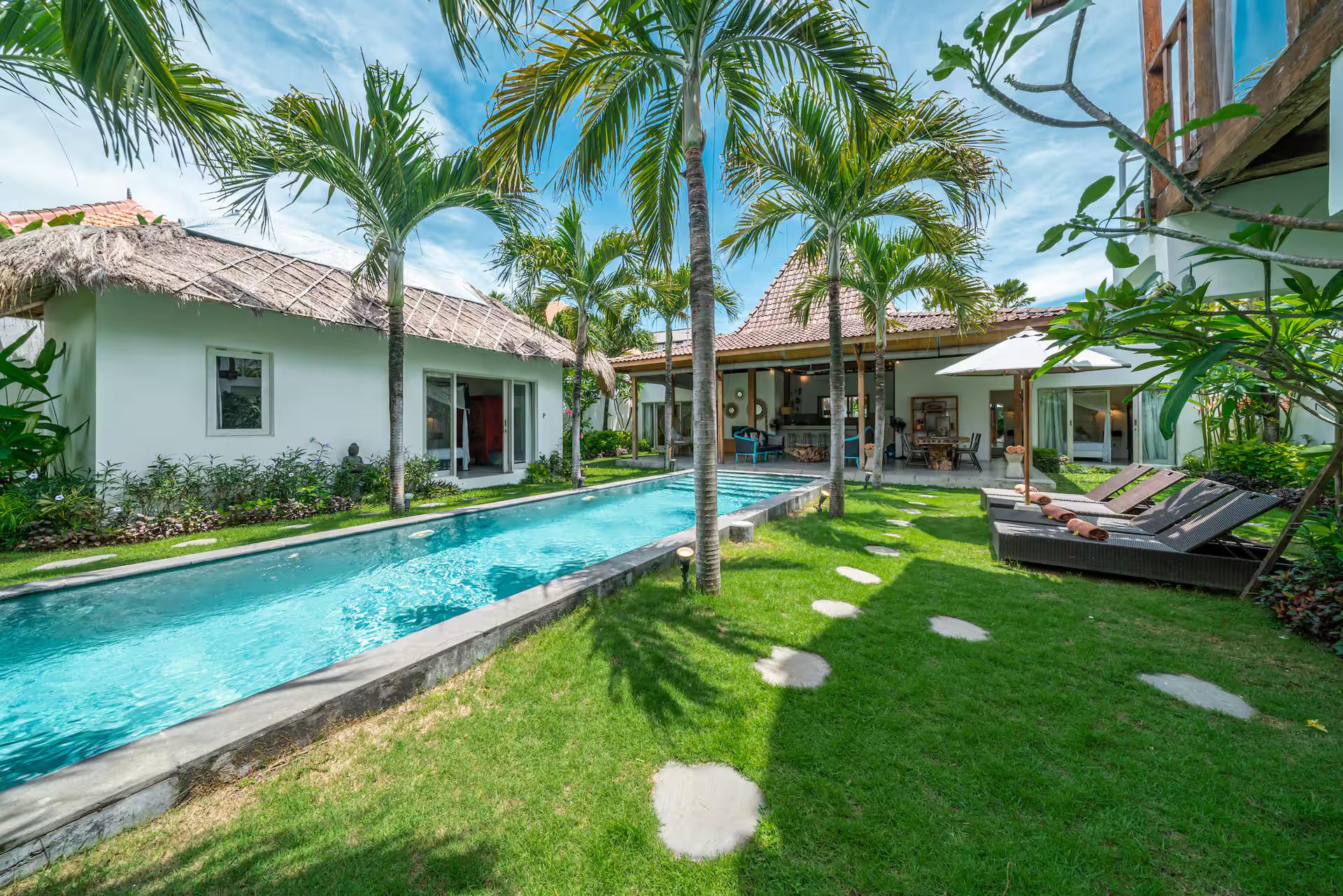 Stepping stones across the lawn to the pool, coconut palms shading both banks