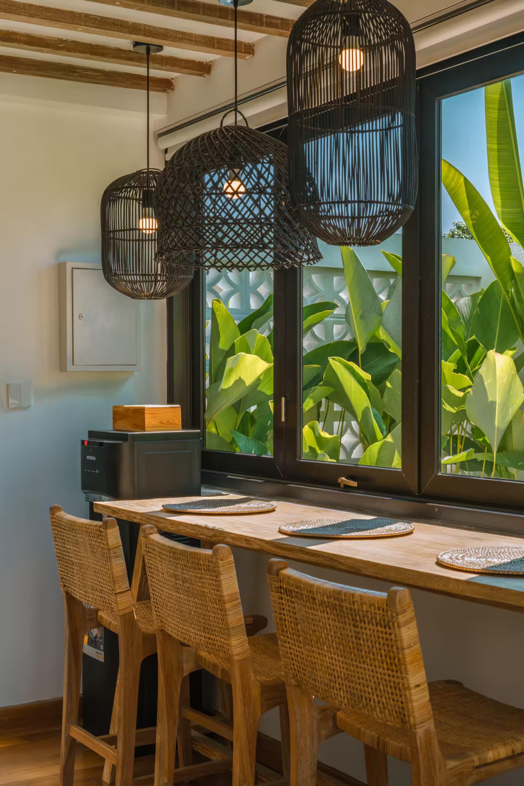 Dining counter with cane stools under two black rattan pendants at Villa Tiny