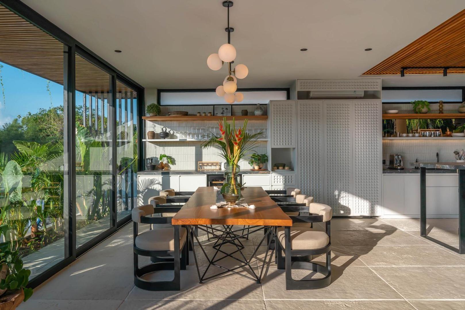 Dining table under a cluster of glass globe pendants, glass walls onto the garden