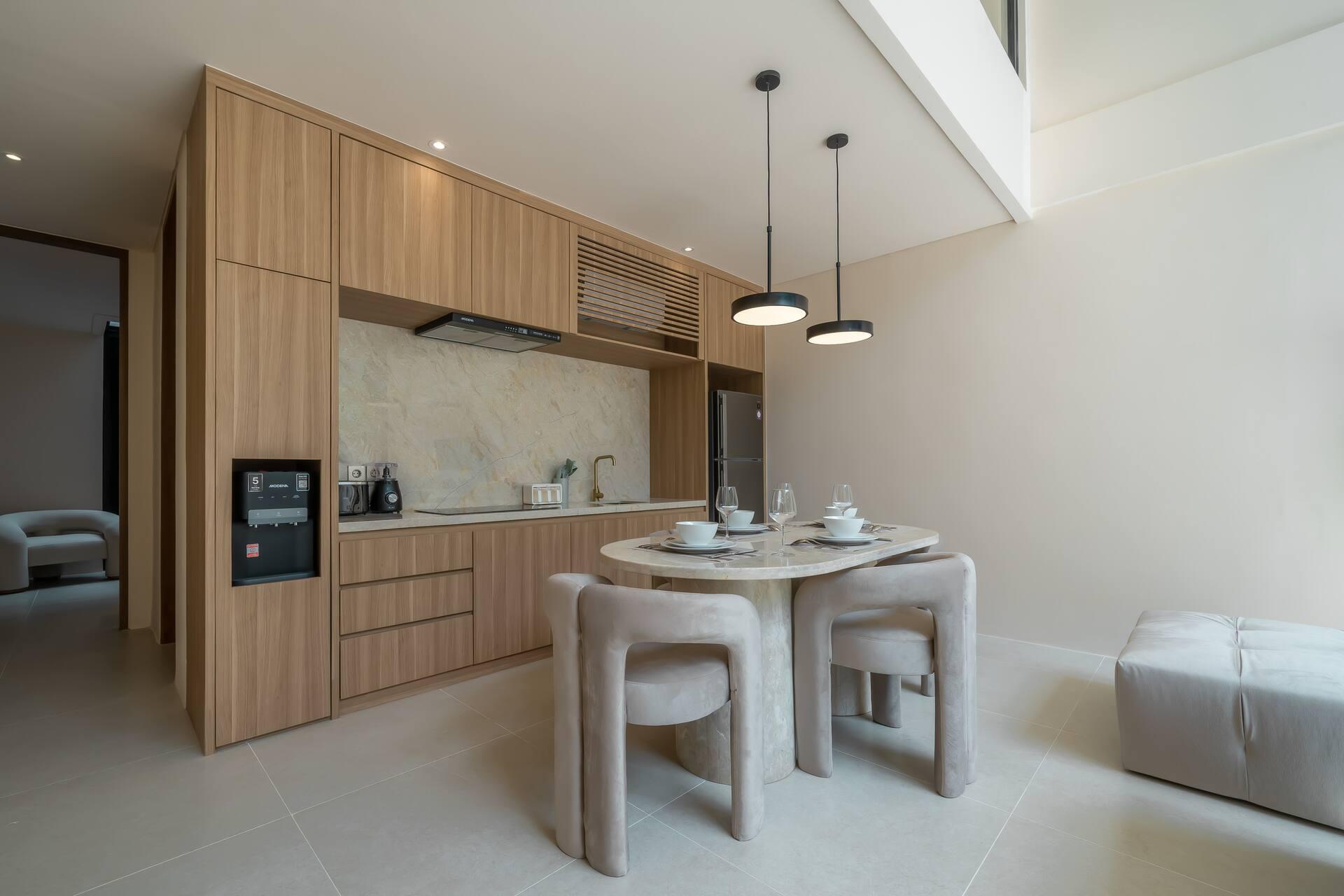 Pale timber kitchen and a round stone table under the double-height void at Enso 4