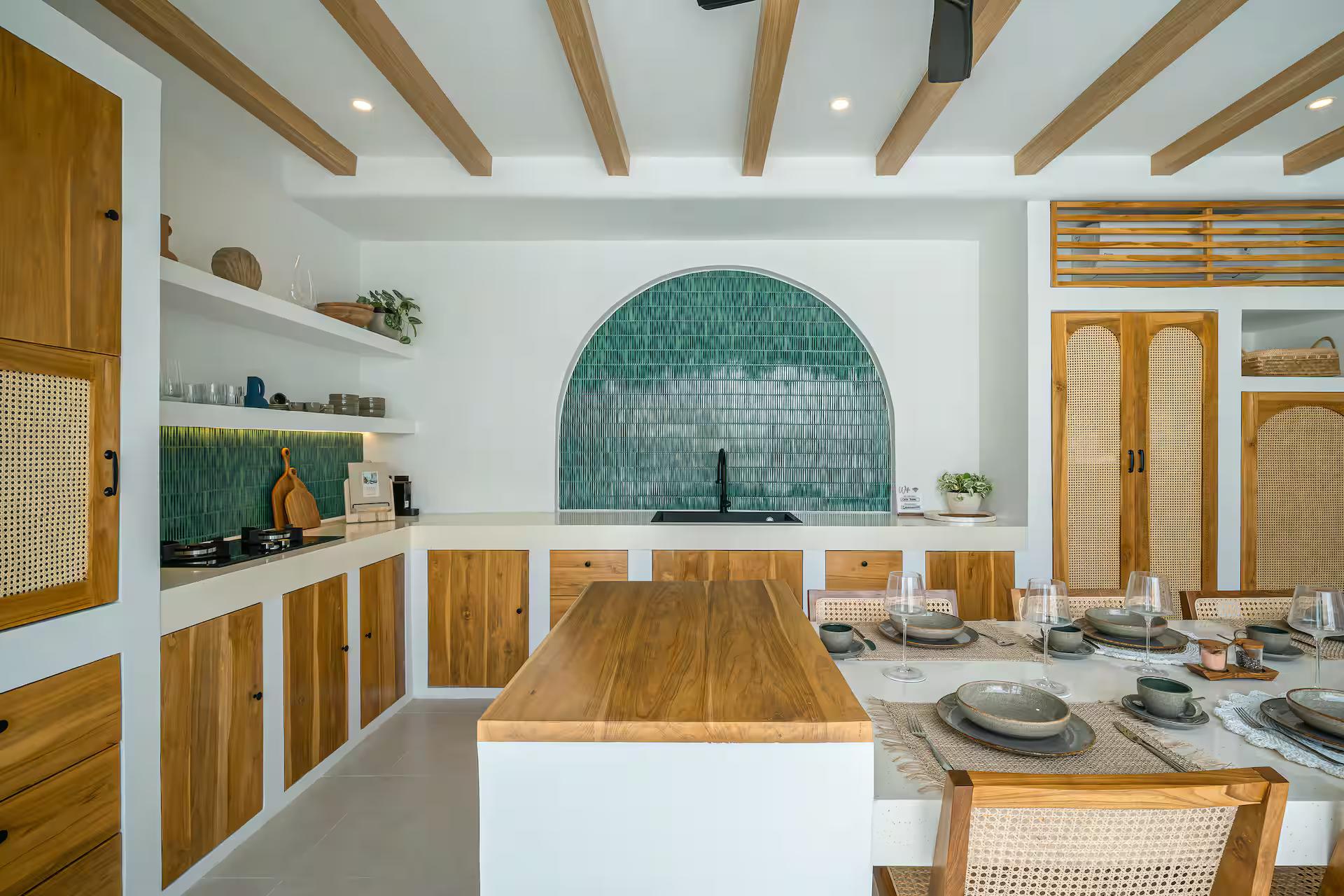 Kitchen at Casa Shams with a green zellige-tiled arch above the hob and a timber island