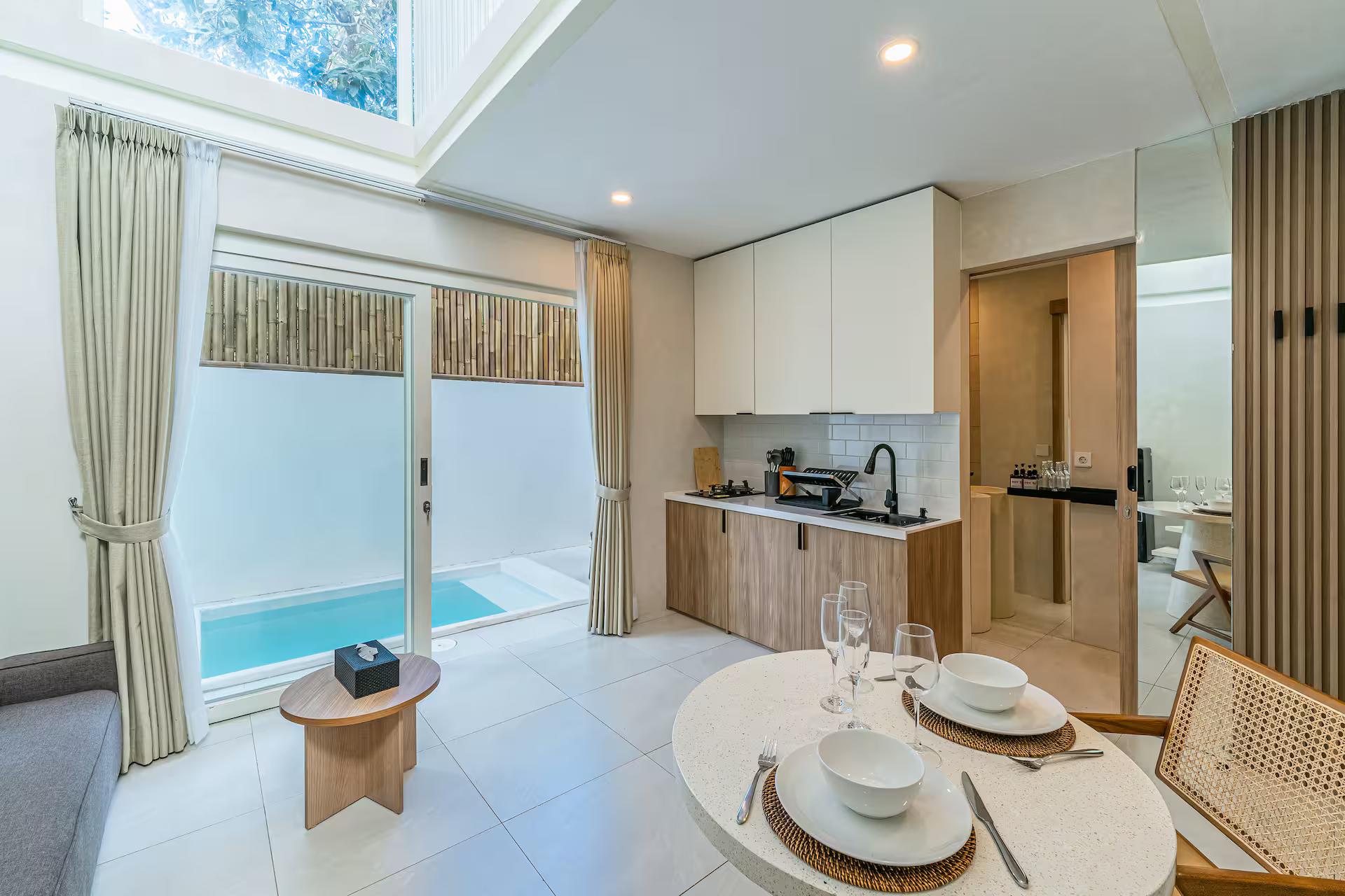 Dining nook under a skylight, the plunge pool visible through full-height glass