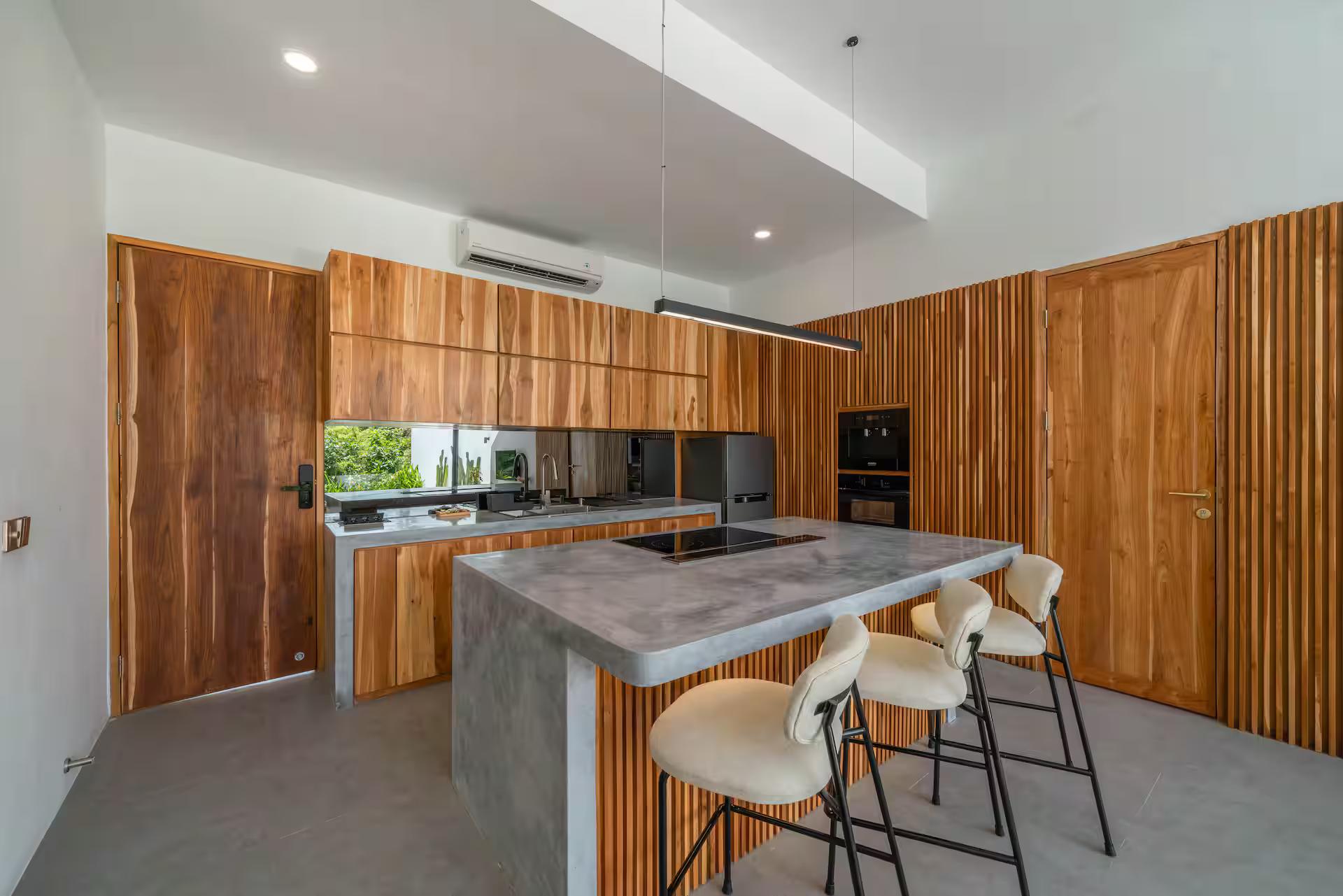 Kitchen in solid timber joinery with a concrete-topped island and three bar stools