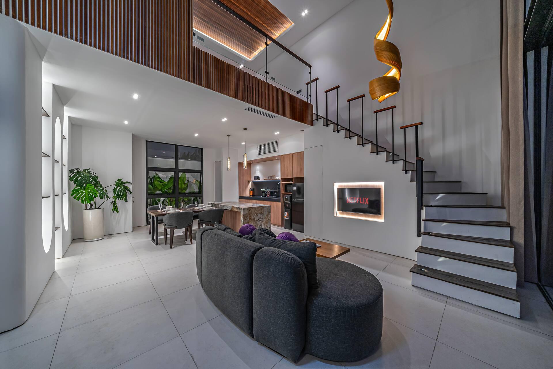 Living room at Aether Villa looking through the two-storey void to the floating staircase above