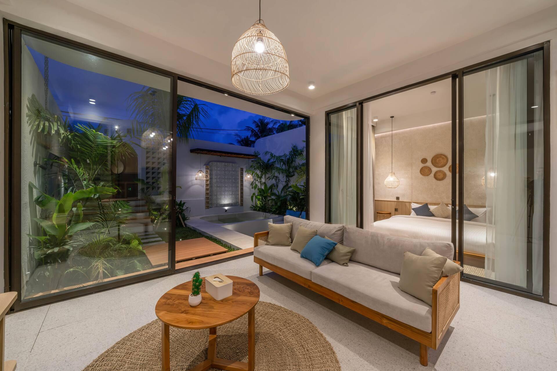 Evening in the living room, with the ground-floor bedroom visible behind its sliding glass doors