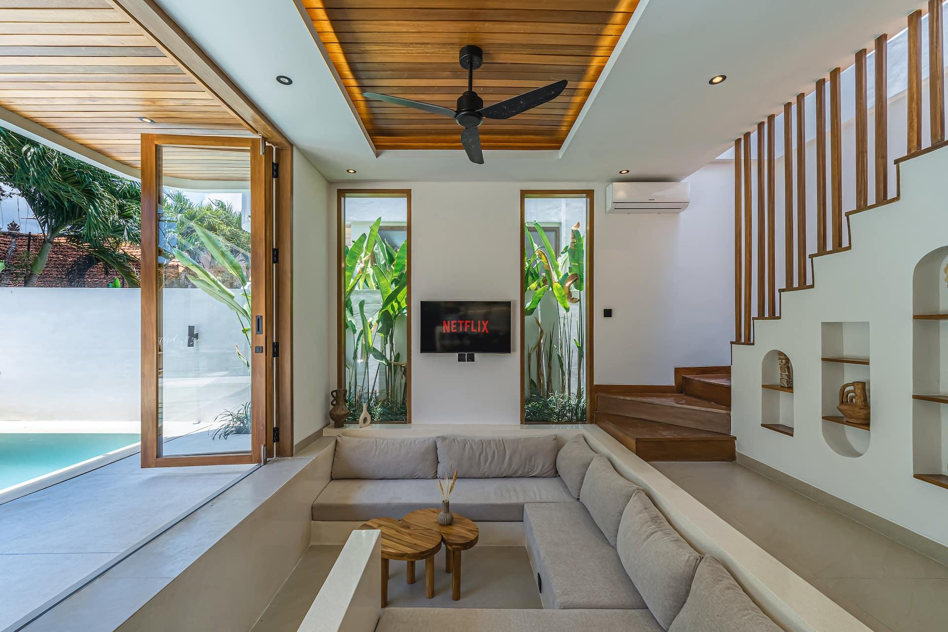 A sunken plaster sofa faces the pool under a raked timber ceiling and slow ceiling fan