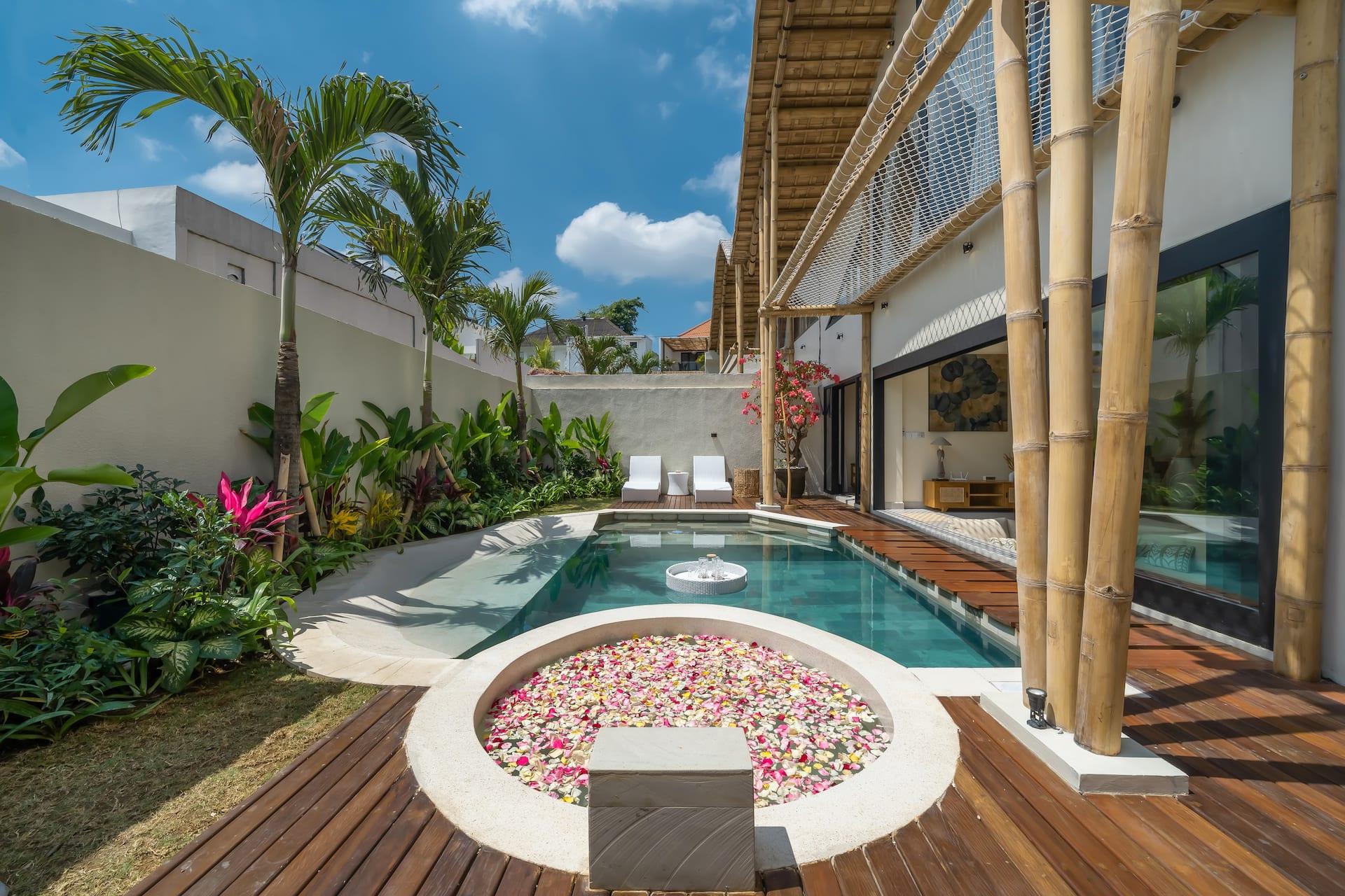 Circular hot tub scattered with frangipani petals, set into the deck beside the pool