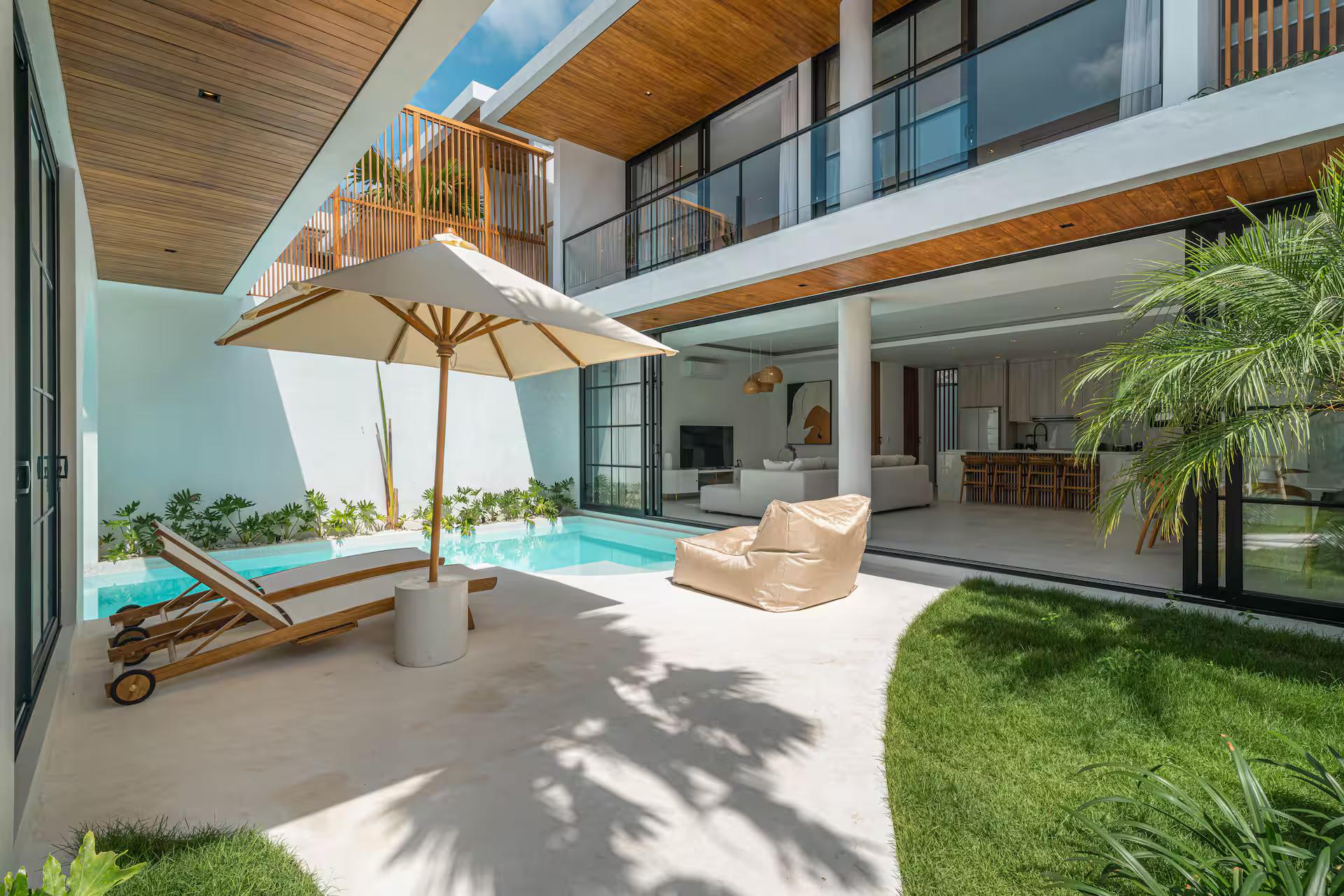 Villa Jenna seen across its lawn, parasol and loungers along the pool terrace