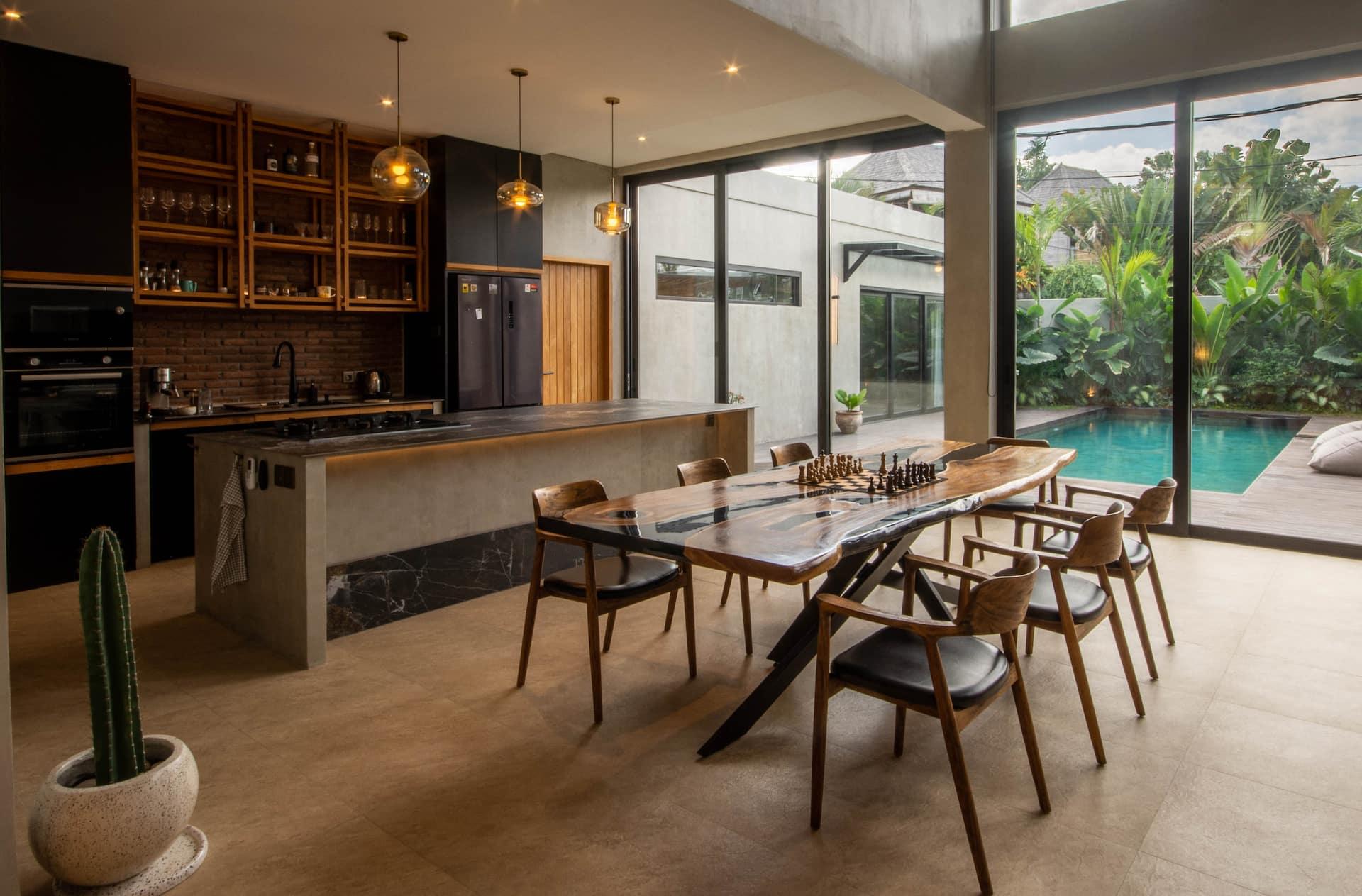 Dining table for eight beside the marble island, with glass doors open to the pool