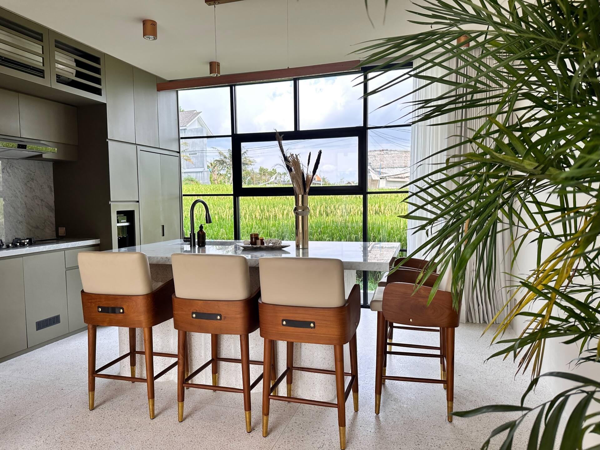 Marble kitchen island with leather bar stools, rice fields filling the window behind