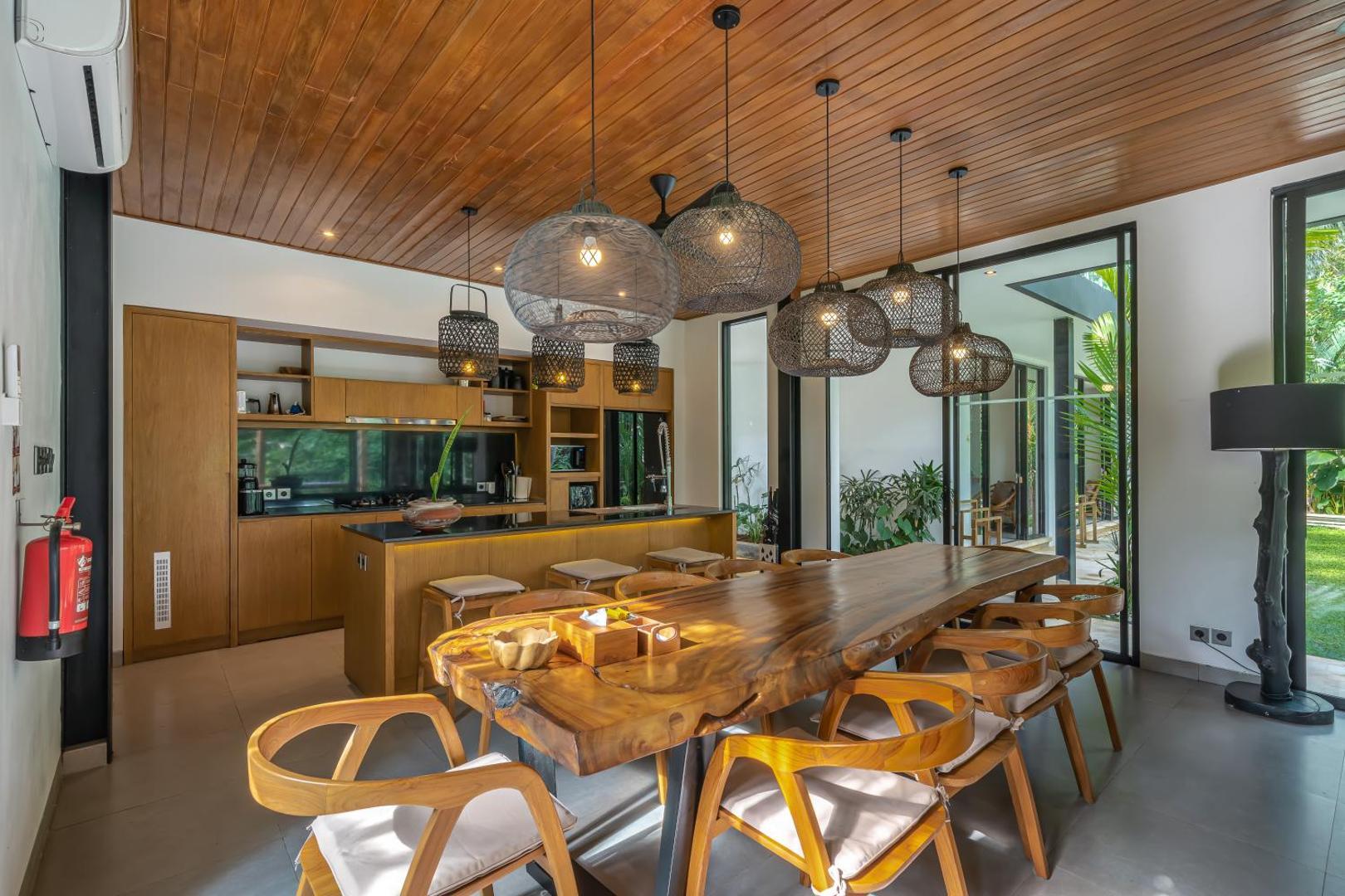 Live-edge dining table for twelve beneath a row of woven cane pendant lights