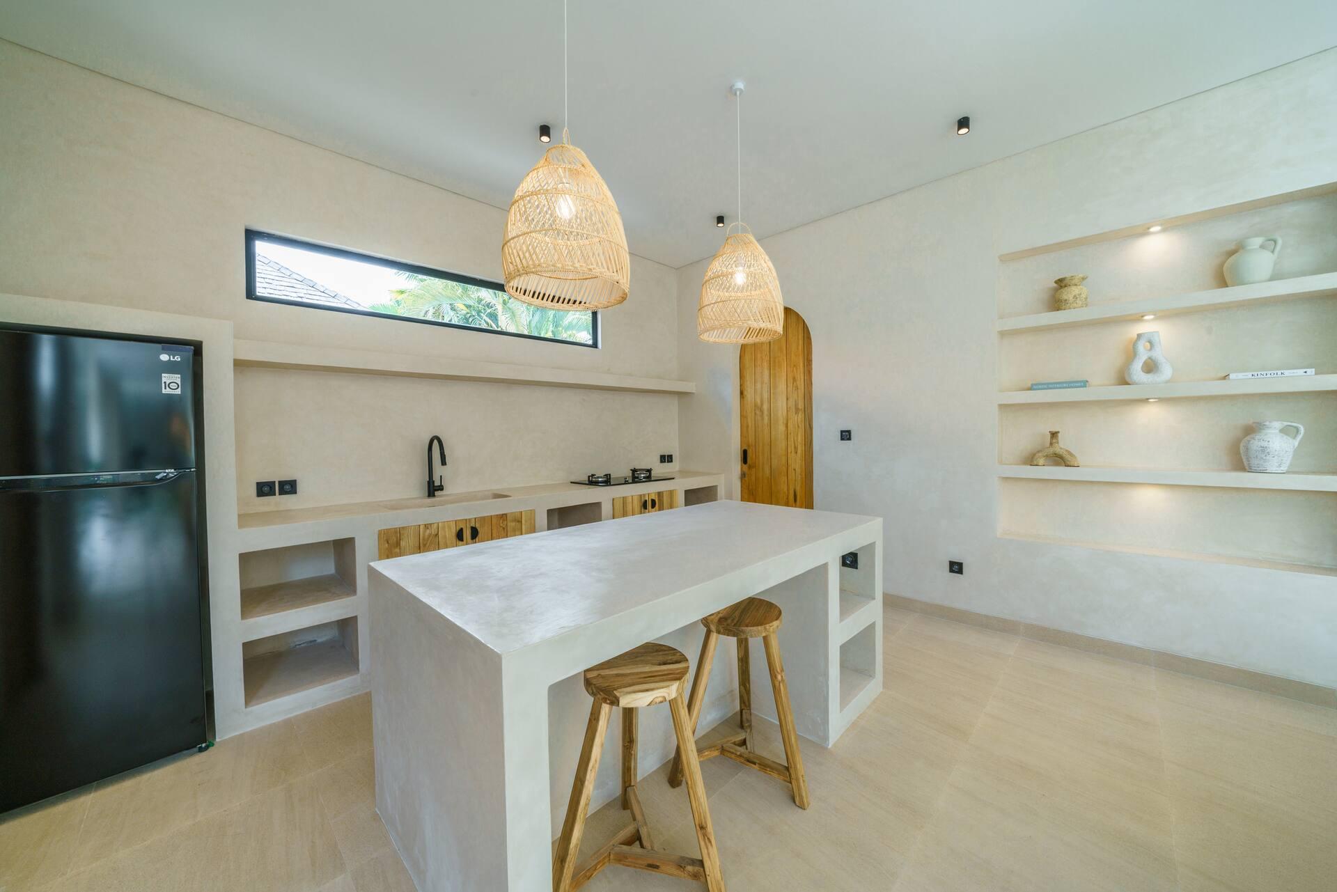 Kitchen island in troweled microcement with timber bar stools and an arched pivot door behind