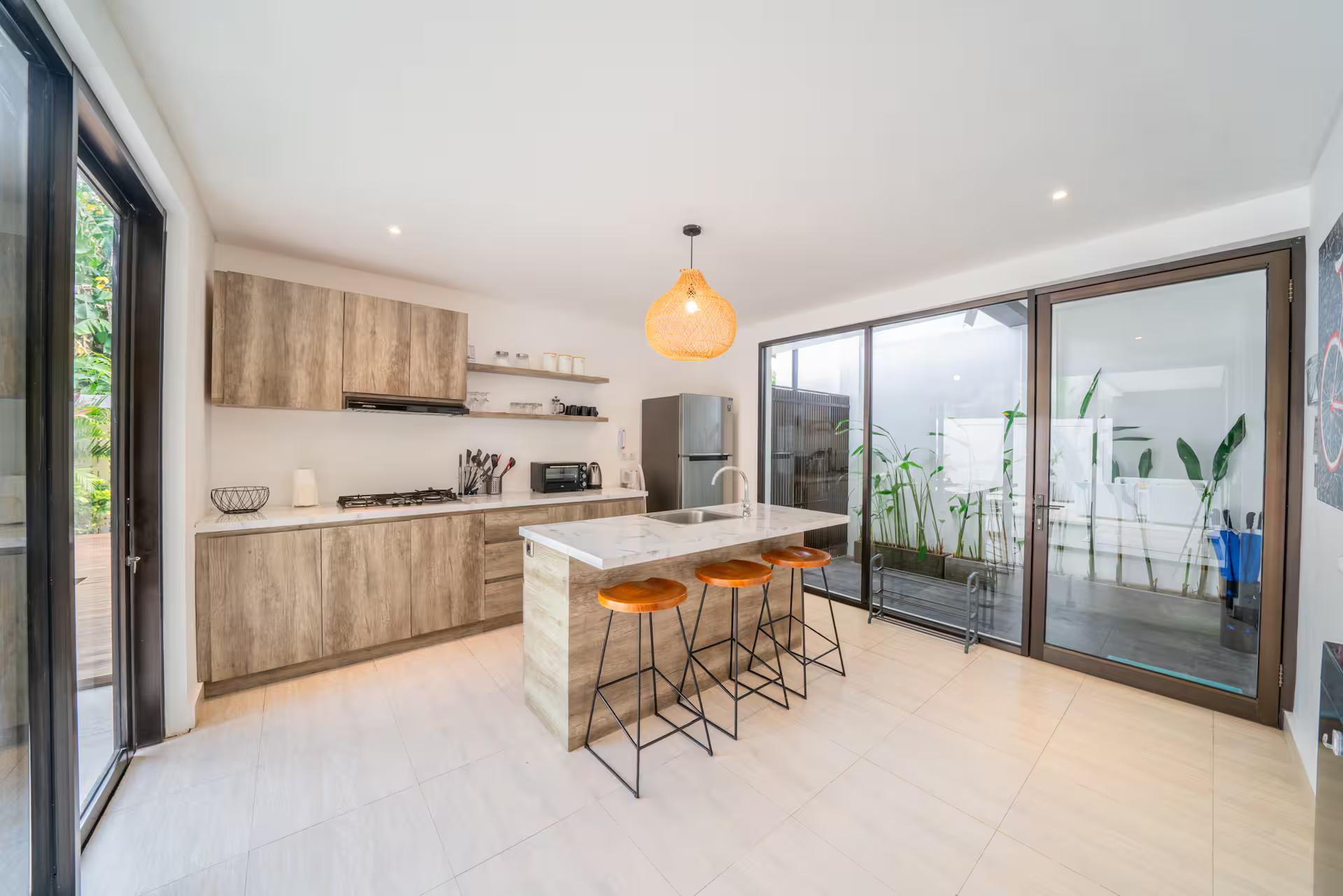 Kitchen island with bar stools and timber cabinetry, sliding glass onto the terrace