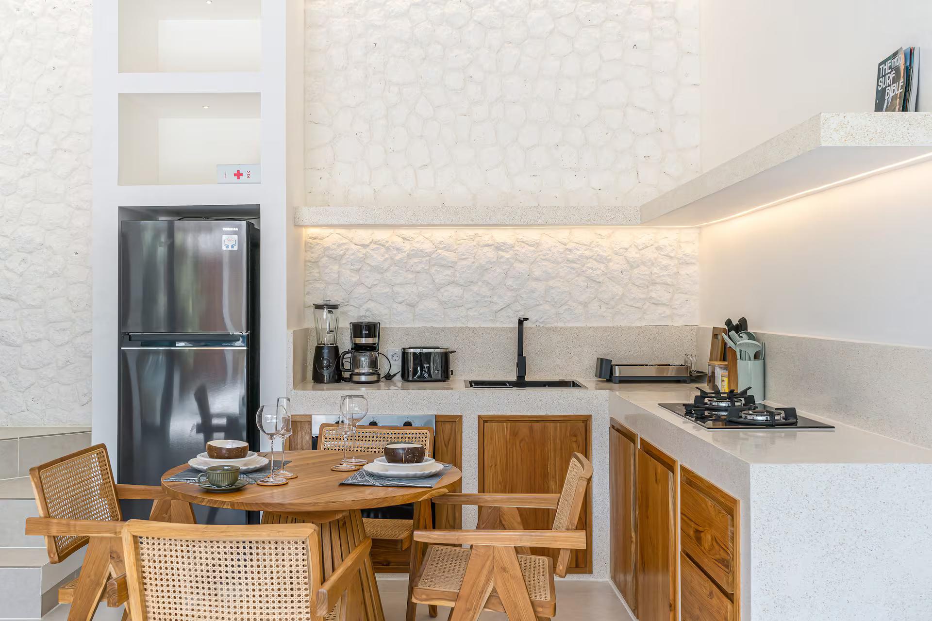 Kitchen in timber cabinetry with a stone counter and a textured white plaster splashback