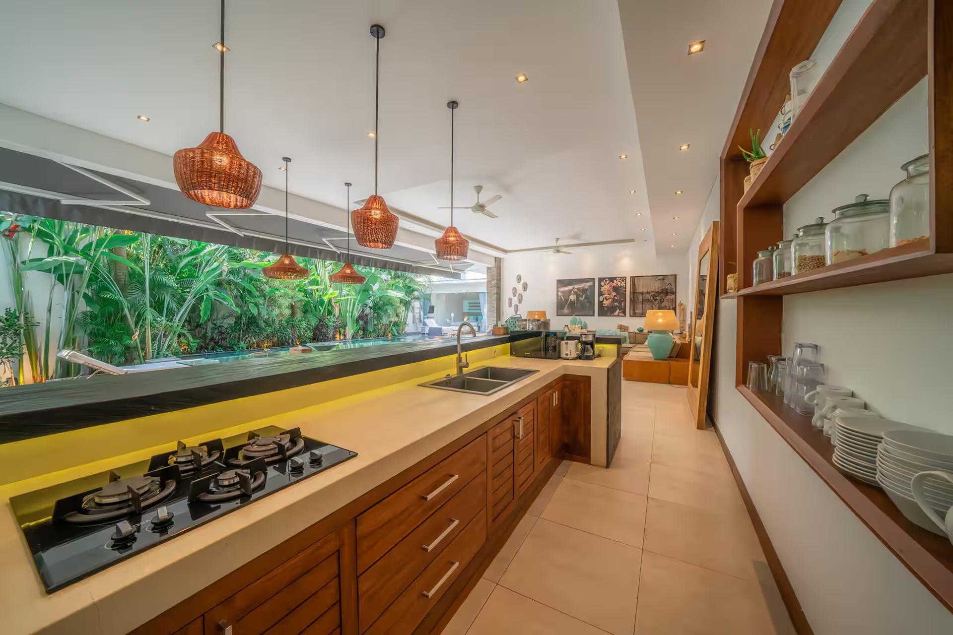 Galley kitchen in teak with a long window over the counter and open shelving
