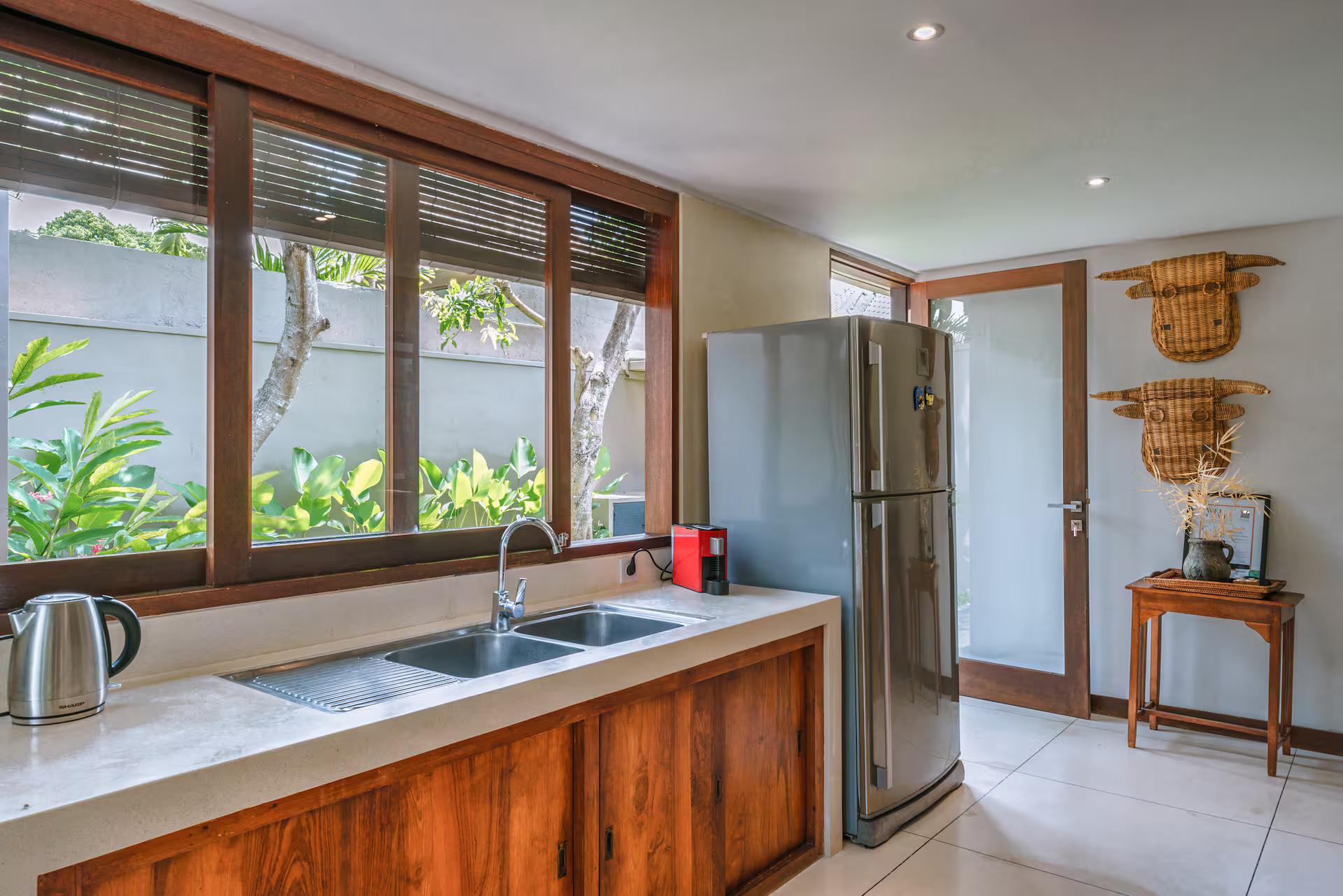Galley kitchen in solid timber with a stone counter and louvred windows onto the garden