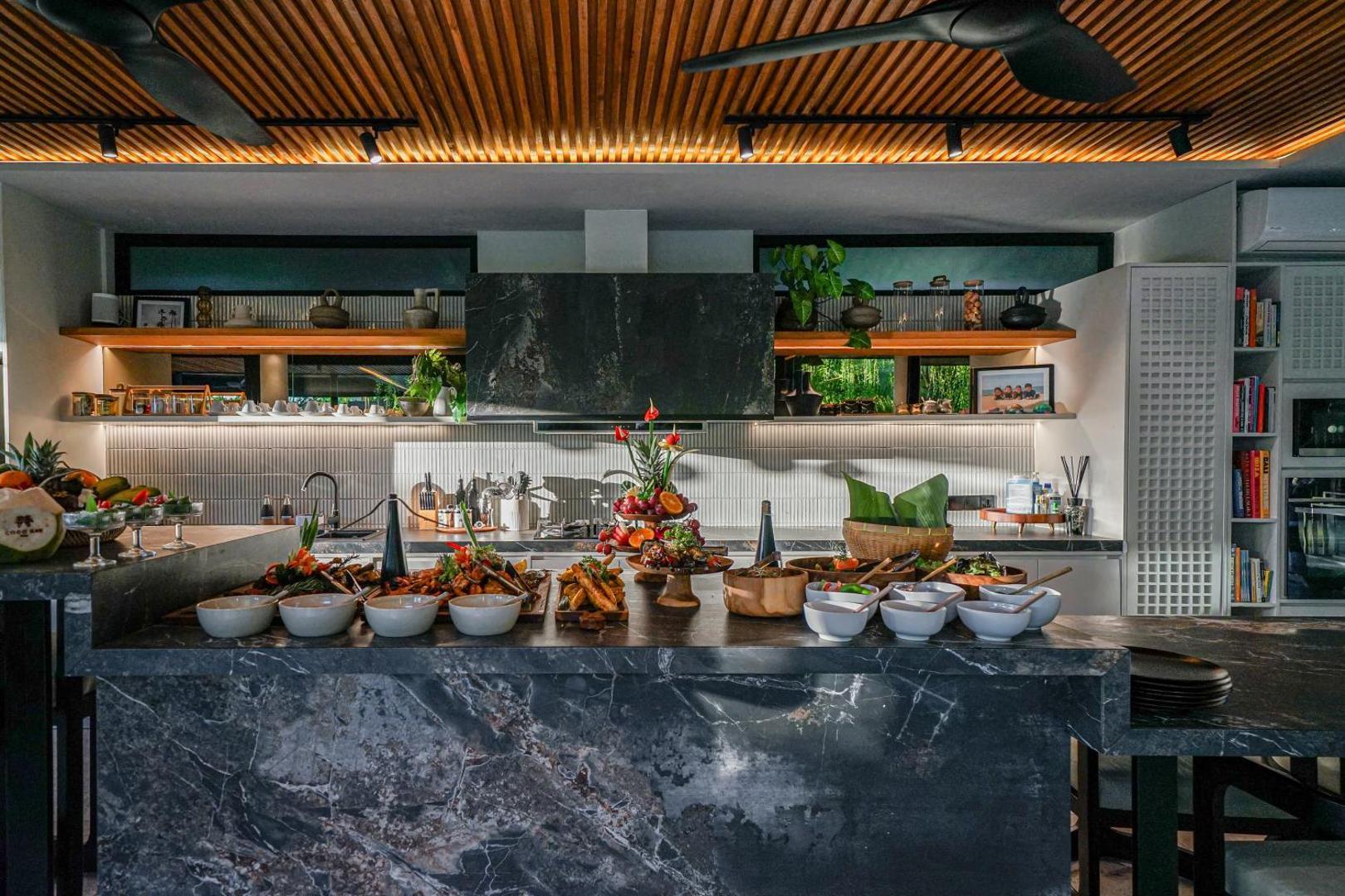 Breakfast laid along the dark marble kitchen island beneath its stone extractor hood