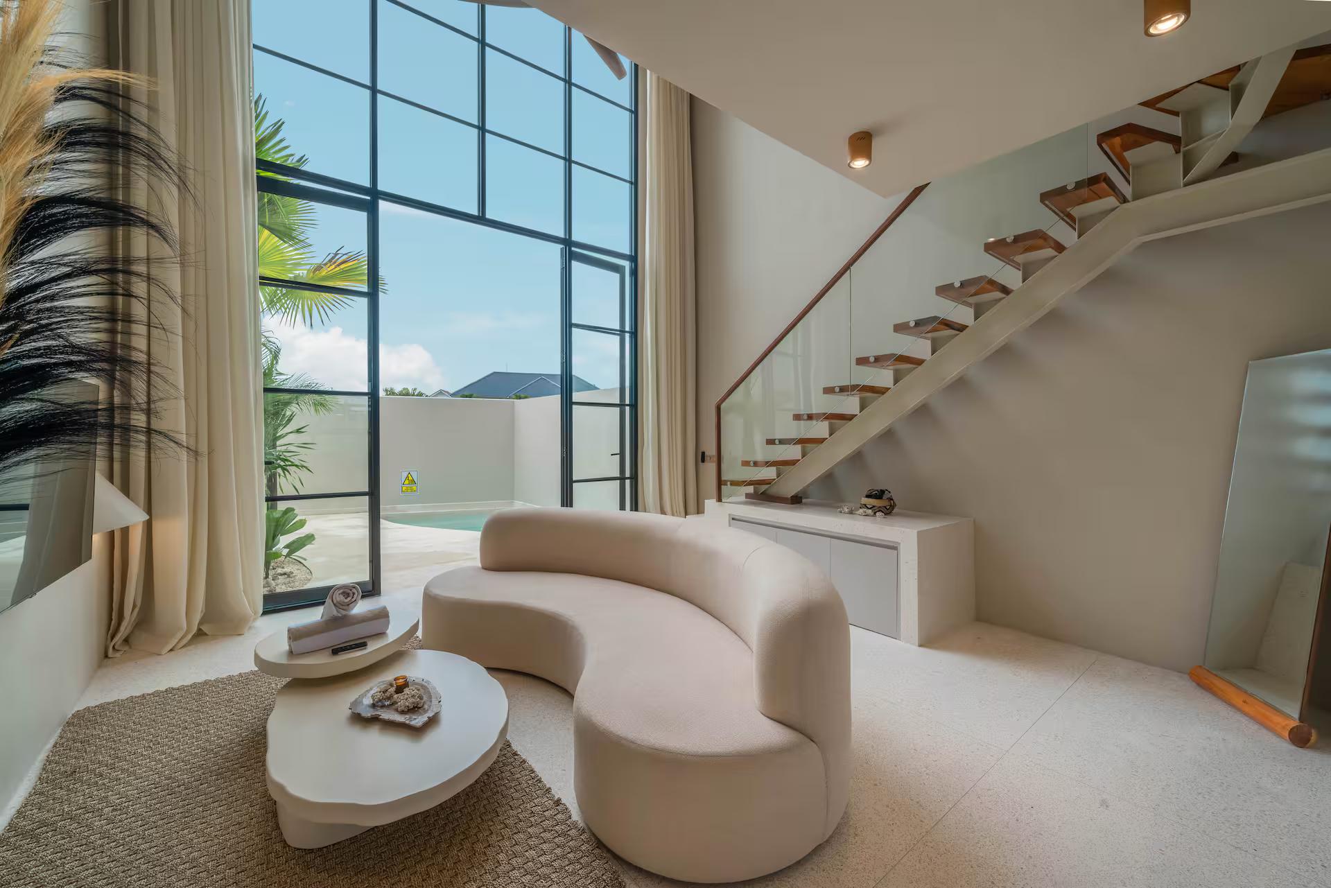 Curved sofa and sculpted tables at Villa Vesna 7, staircase climbing to the mezzanine