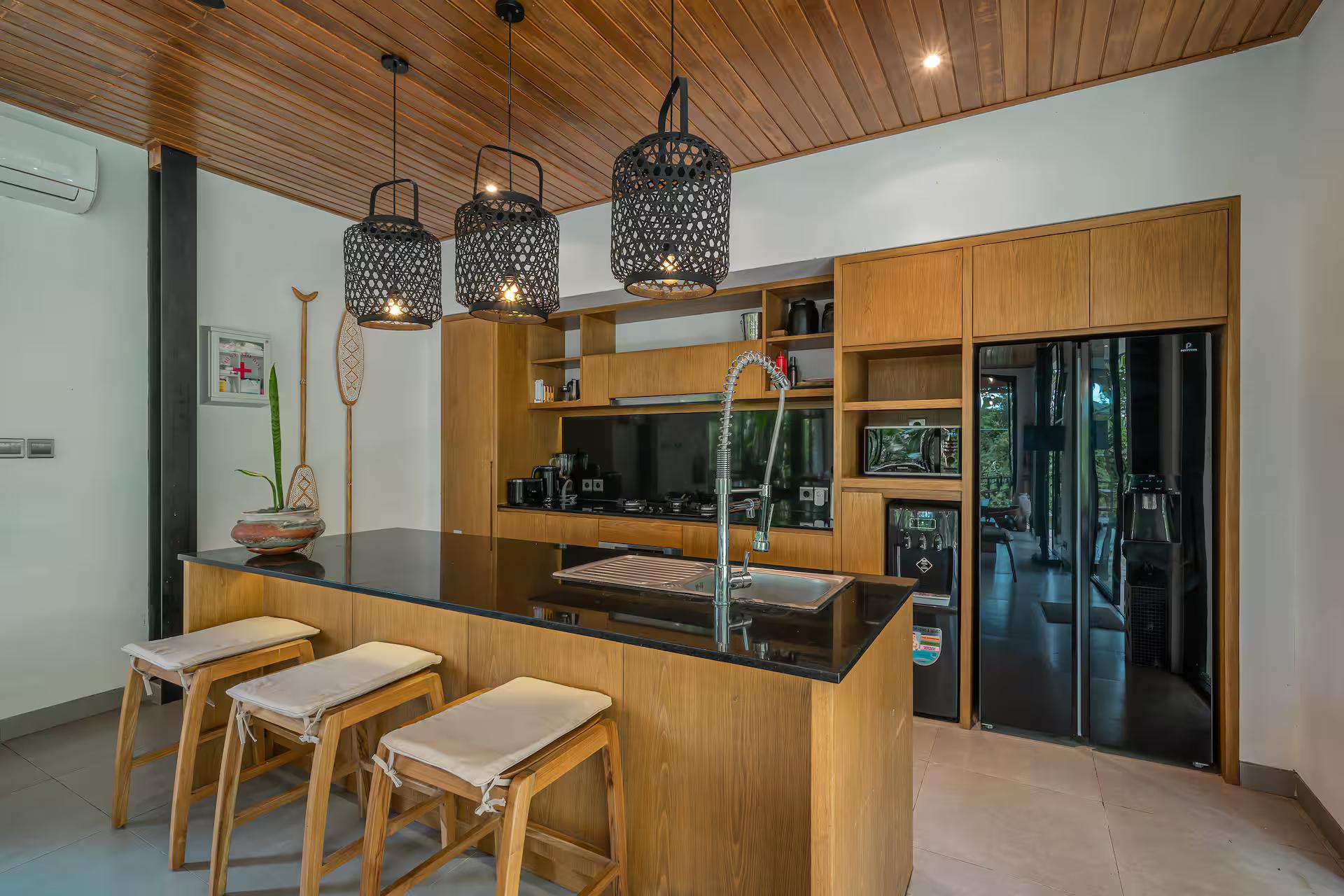 Kitchen island in black stone and timber with bar stools at Villa Yuka