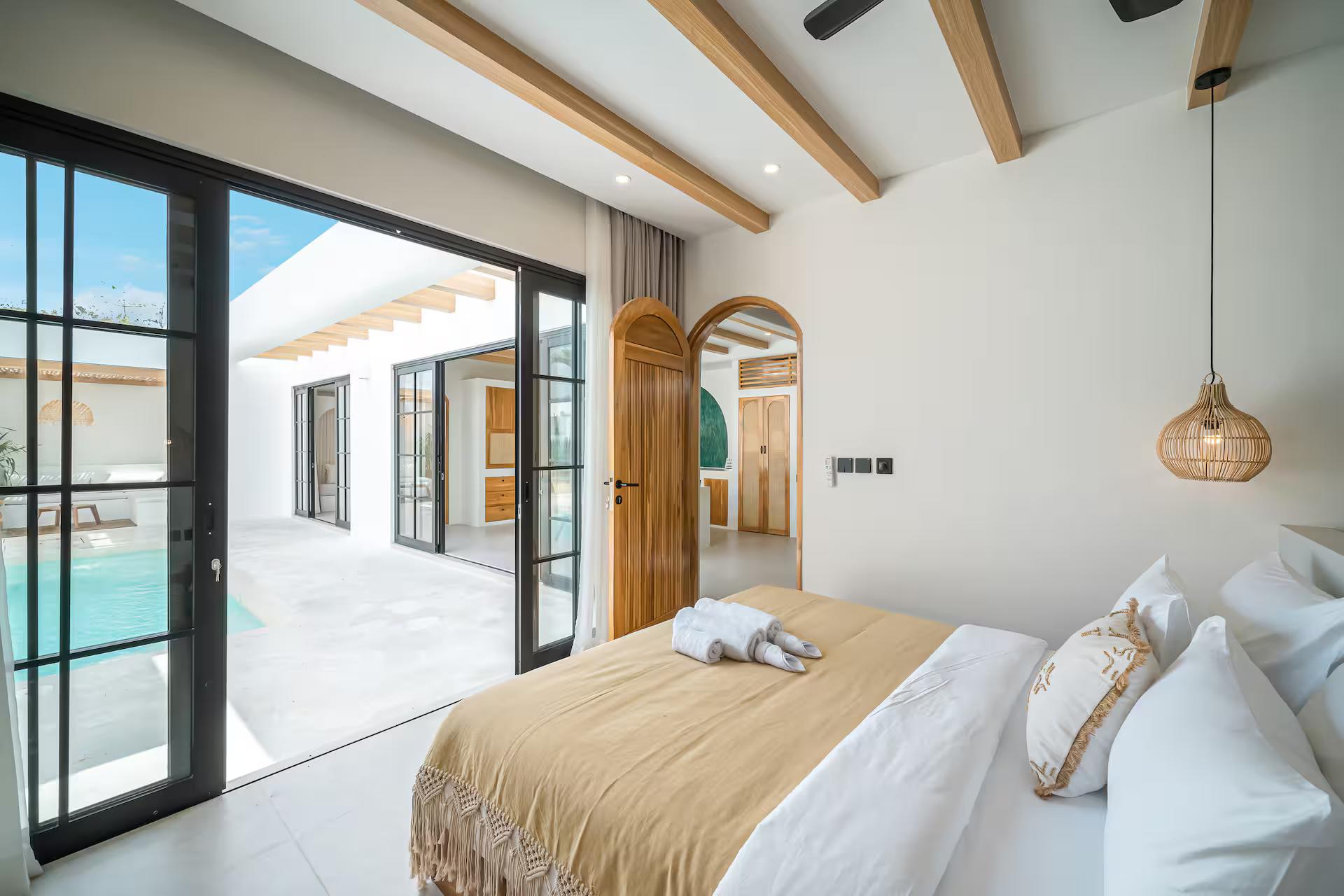 Second queen bedroom, steel-framed doors folded open onto the pool terrace