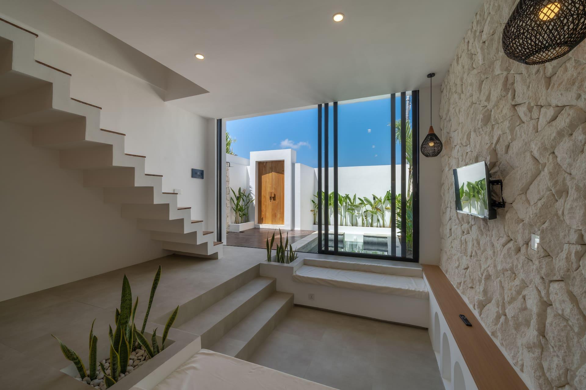 Living room glass doors opening to the pool deck, with the tall timber entrance door beyond
