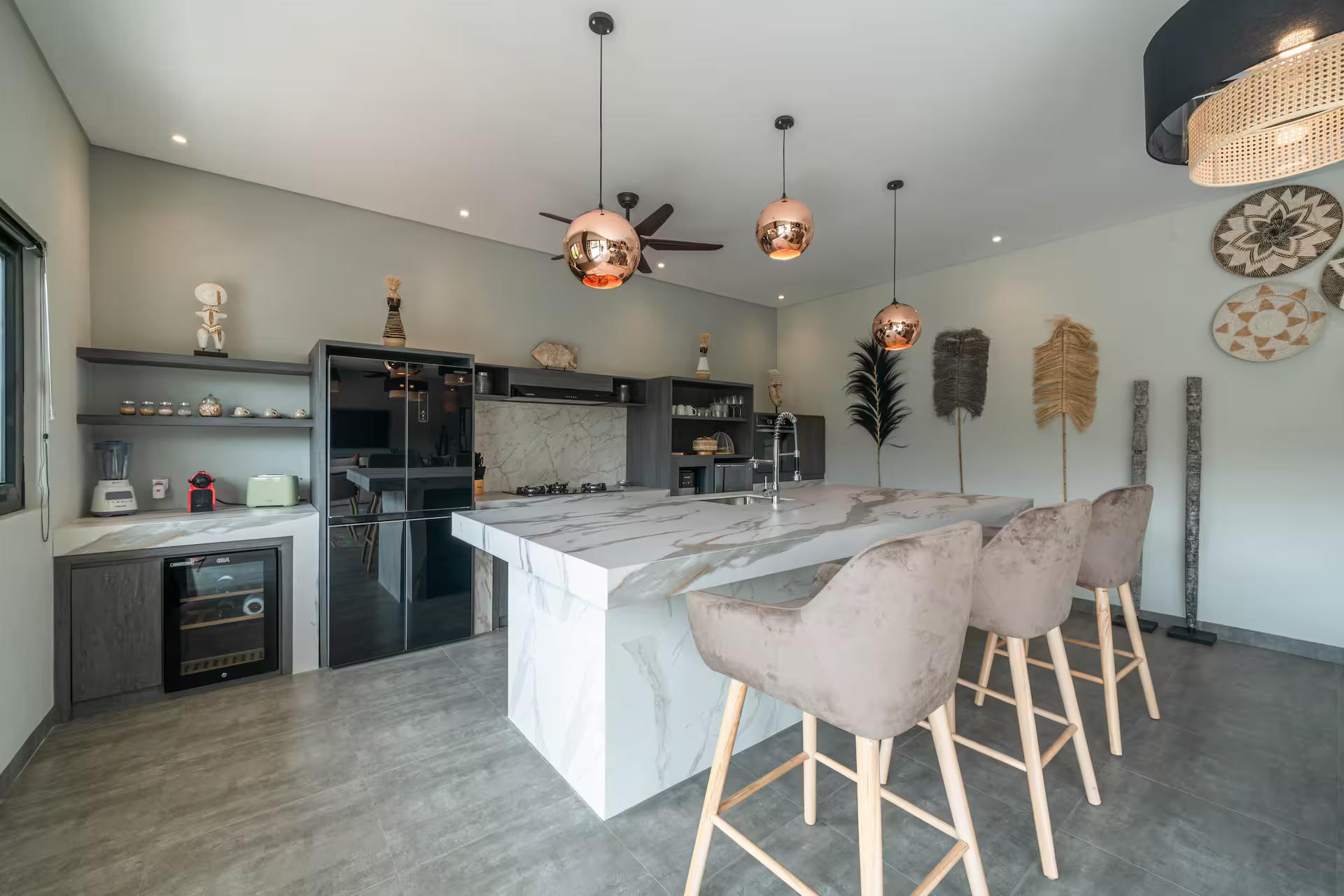 Marble-topped kitchen island with bar stools under copper globe pendants