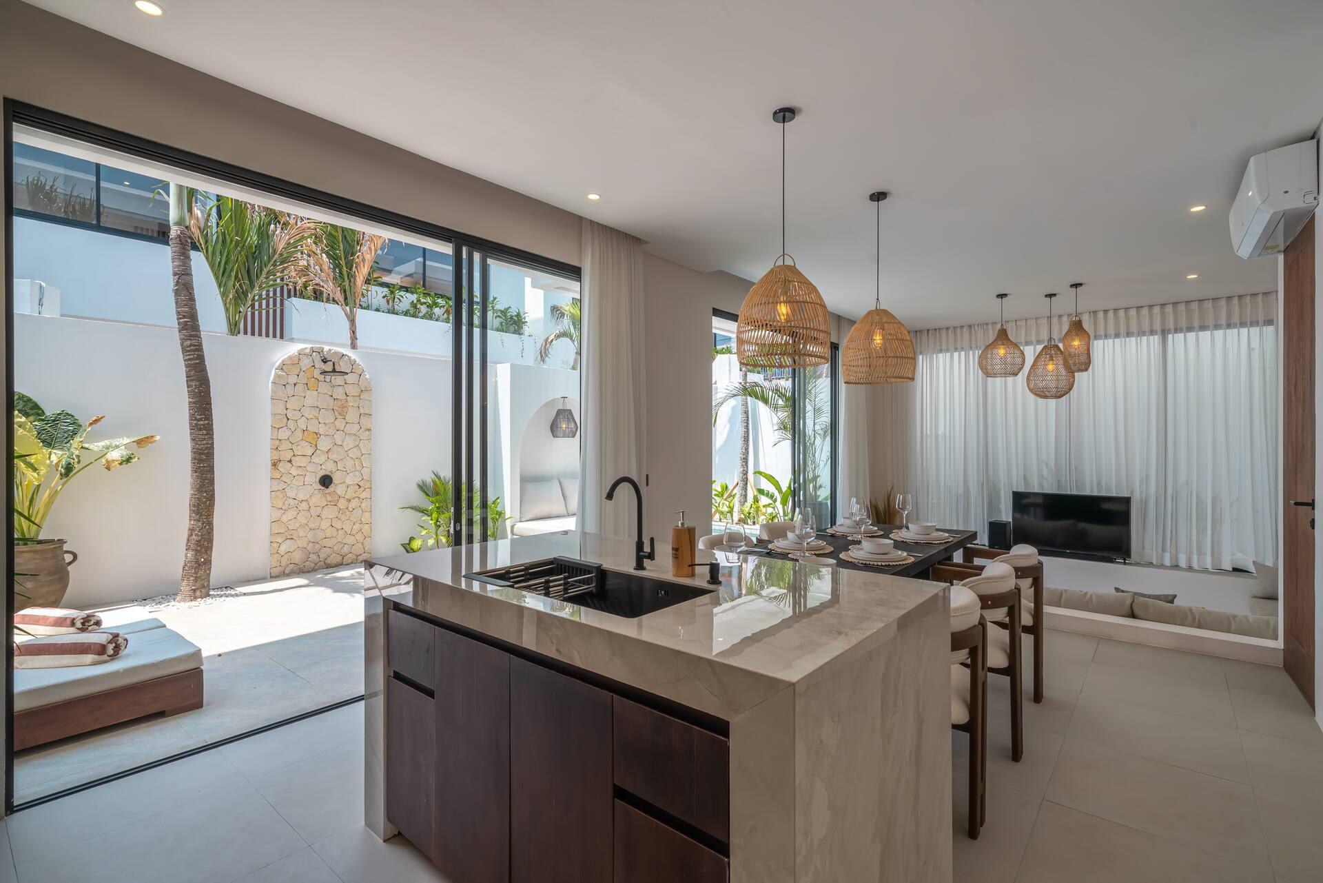 Kitchen island with a pale marble-look top and dark timber base, the sliding glass open to the pool