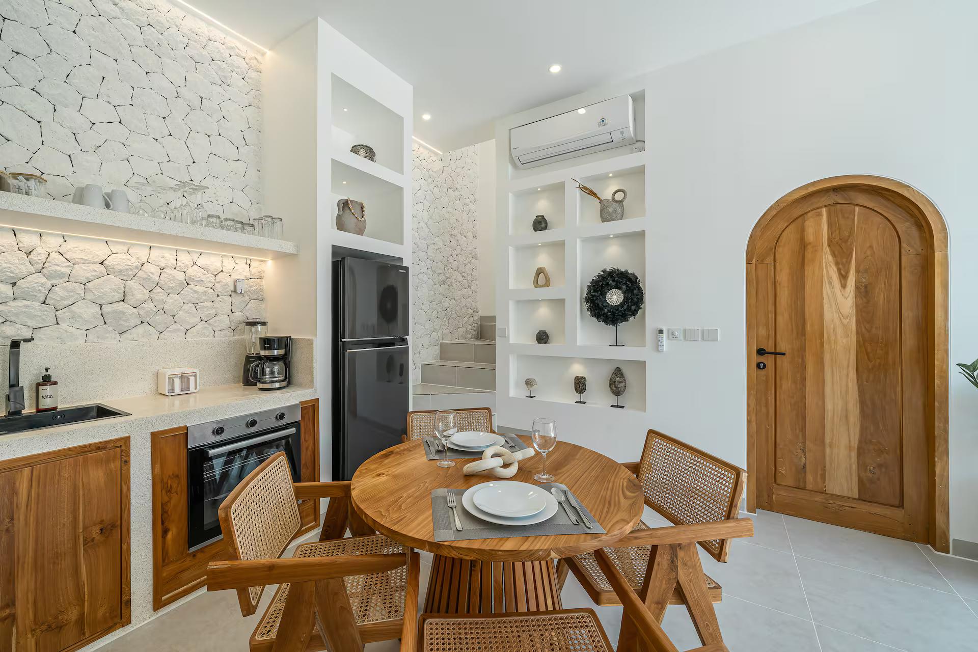 Kitchen in warm timber with an oven, arched niches and an arched solid-timber door