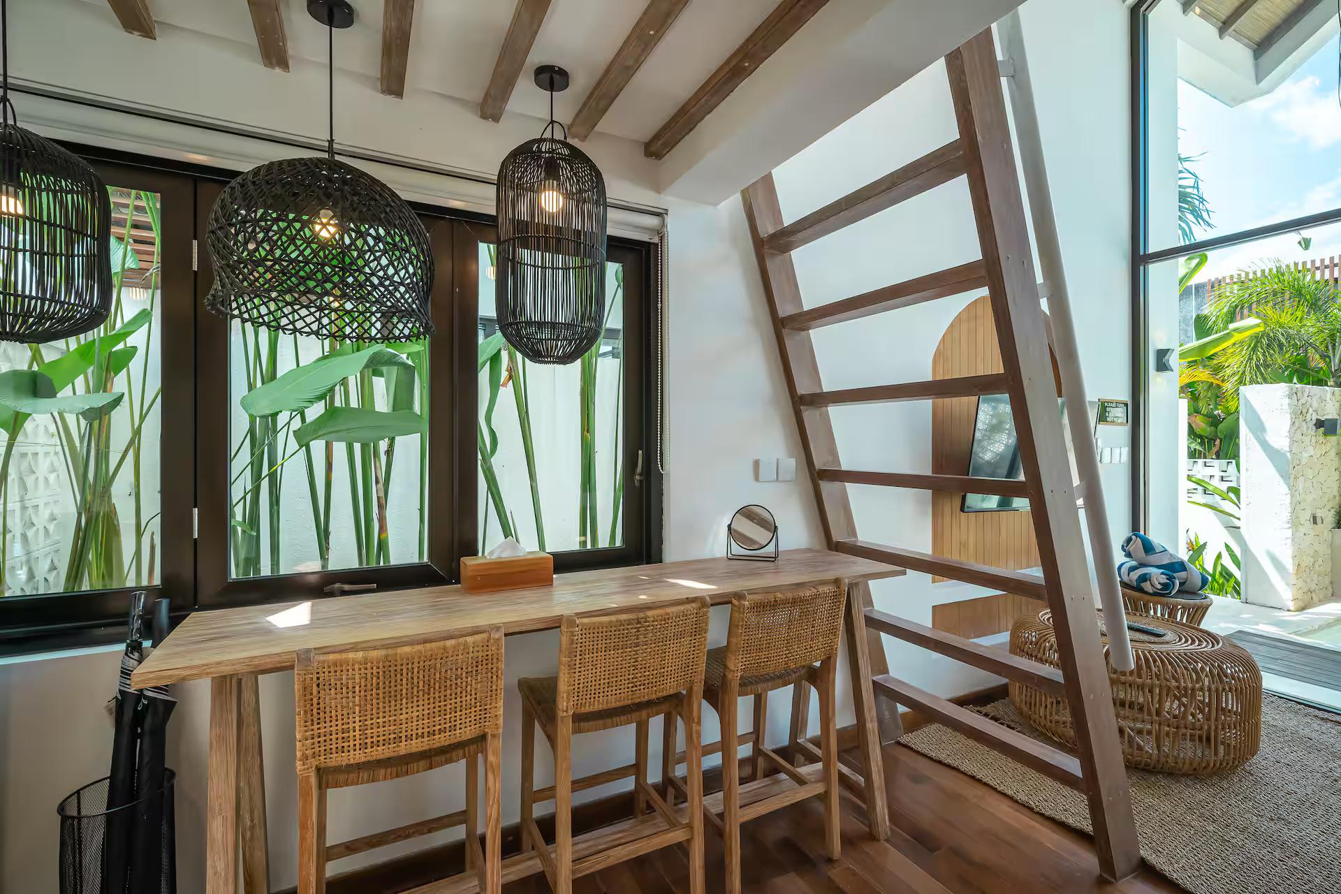 Dining counter with rattan bar stools under black woven pendants by the window
