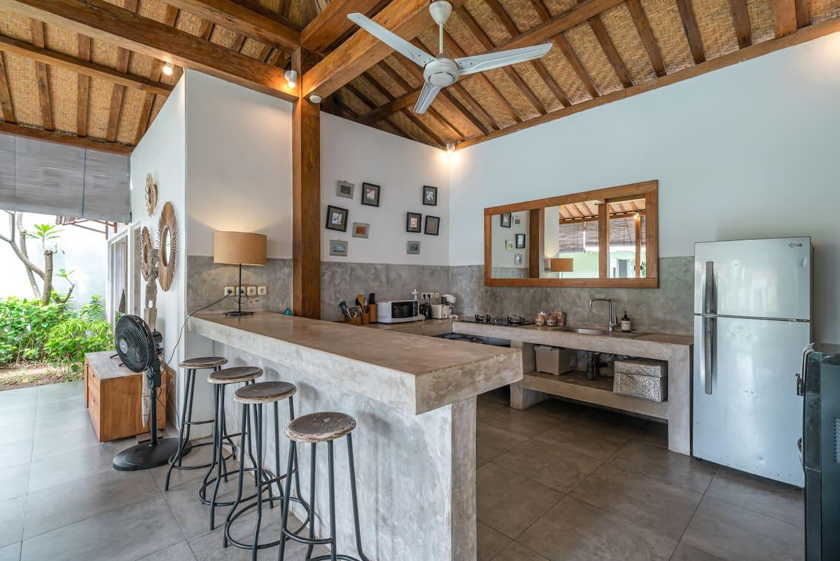 Poured-concrete kitchen island with metal bar stools under the pavilion roof