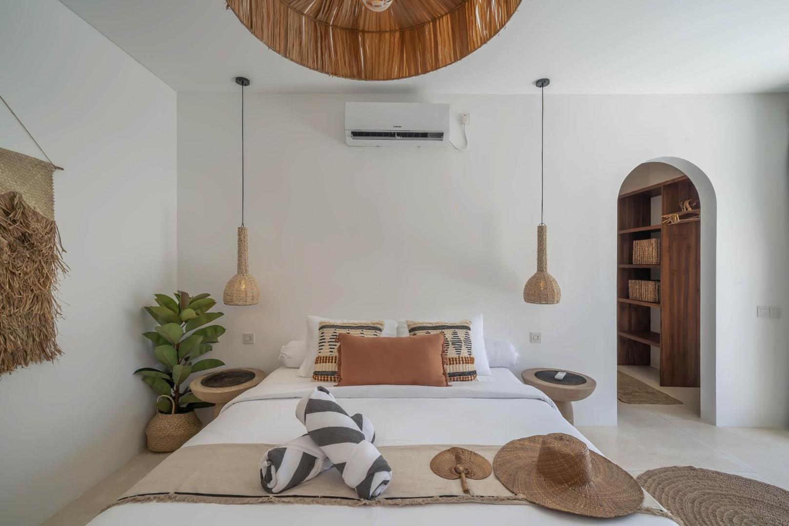 Second king bedroom under an arched alcove with rattan pendants and woven wall art