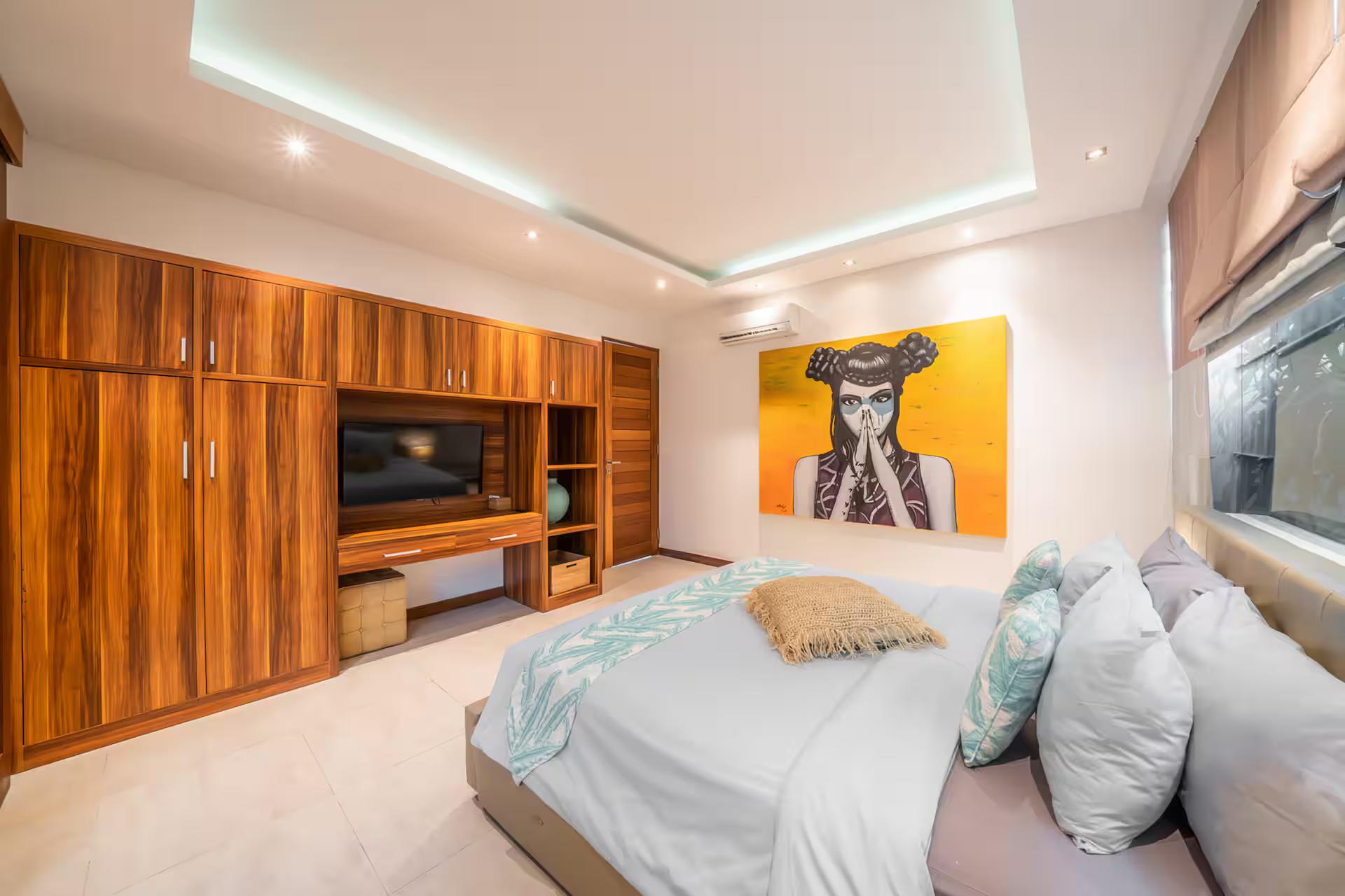 Bedroom fitted in full teak joinery with a wall-mounted TV and a portrait canvas