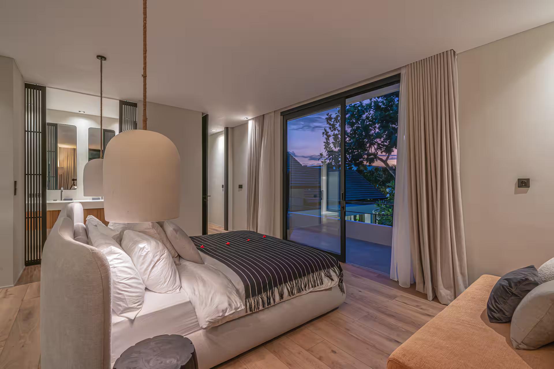 Bedroom with a black-striped throw, timber floor and a sculptural plaster pendant lamp