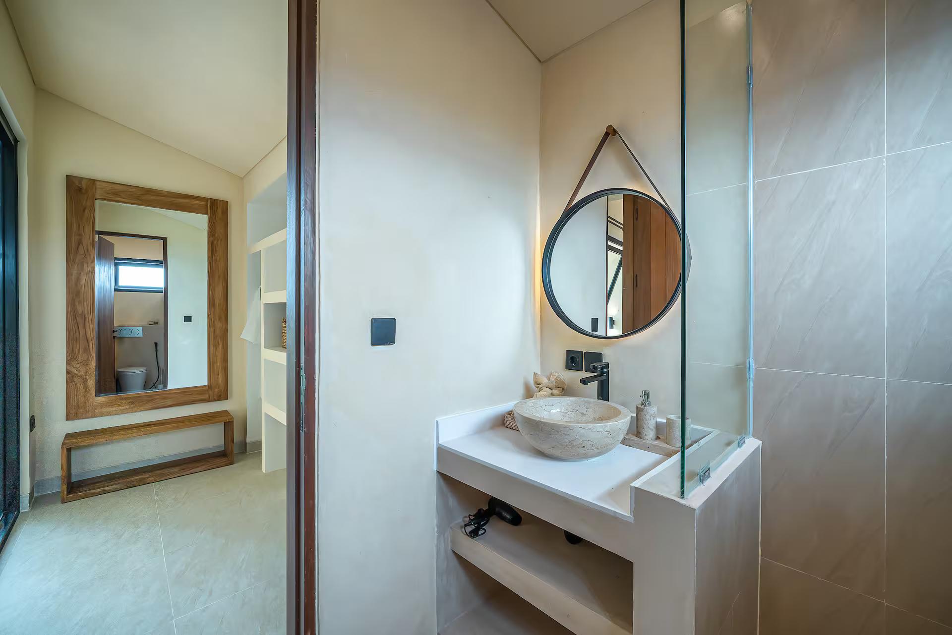 En-suite with a stone bowl basin, a teardrop mirror and a glass shower under a slot window