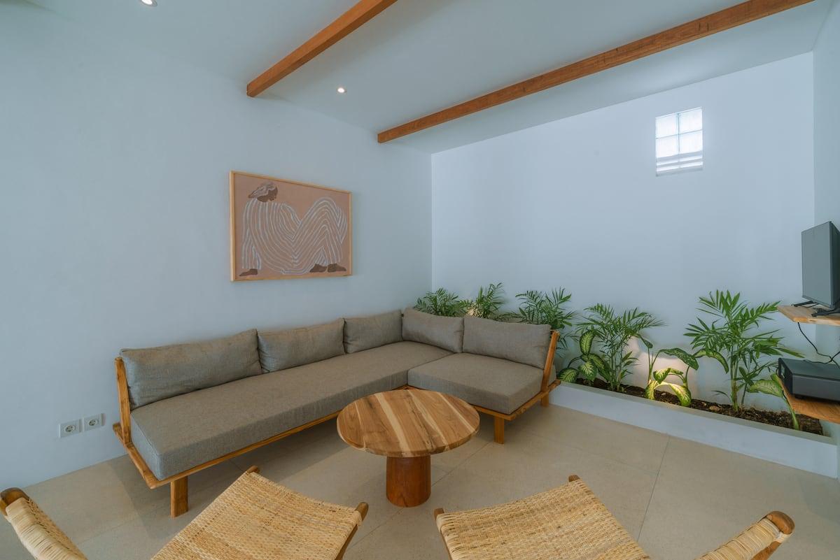 First-floor living area at Villa Eliad, an L-shaped sofa lined with potted greenery