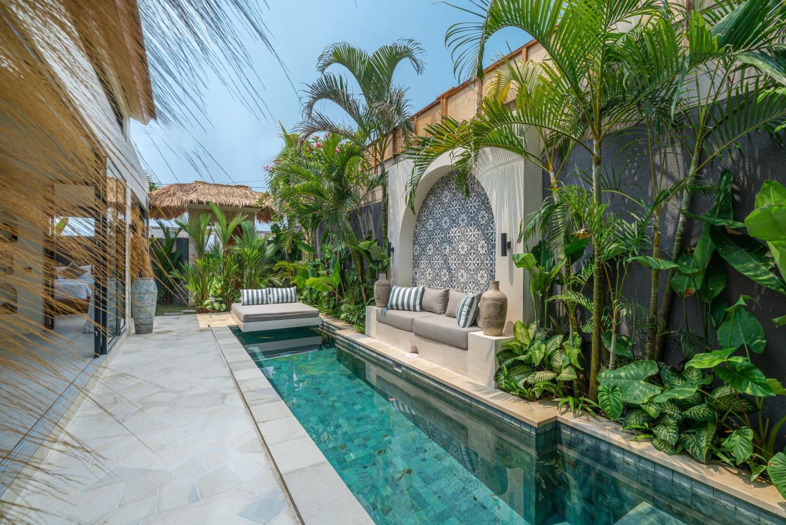 The pool at Villa Isly seen along the stone wall, banana palms crowding the water