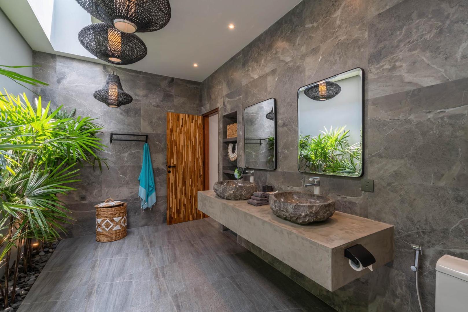 Grey marble bathroom with twin carved stone basins and planting against the glass
