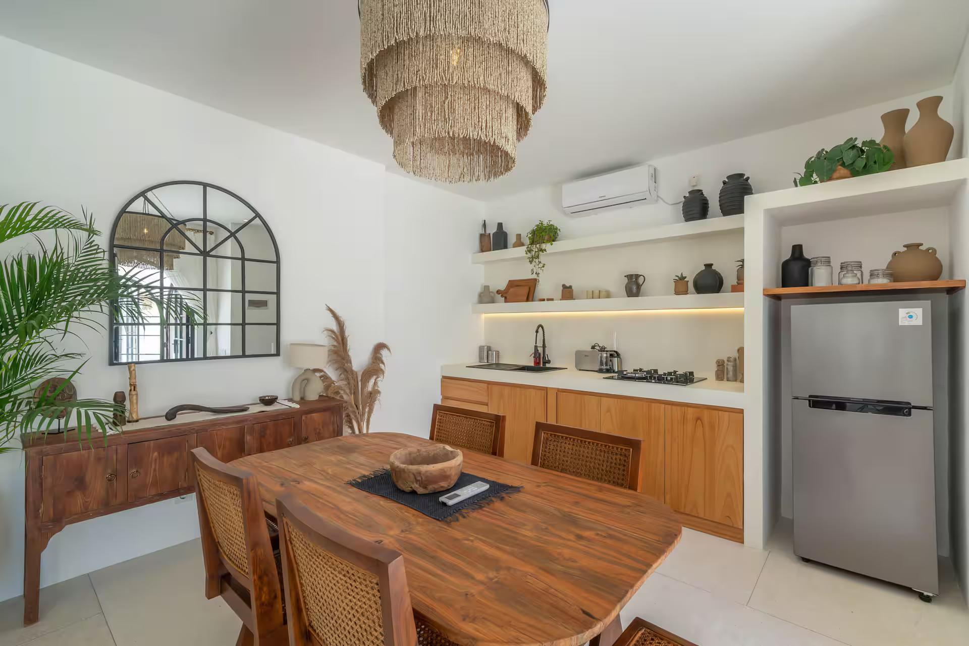 Timber dining table beside the kitchen at Villa Heiwa, lit plaster shelves above