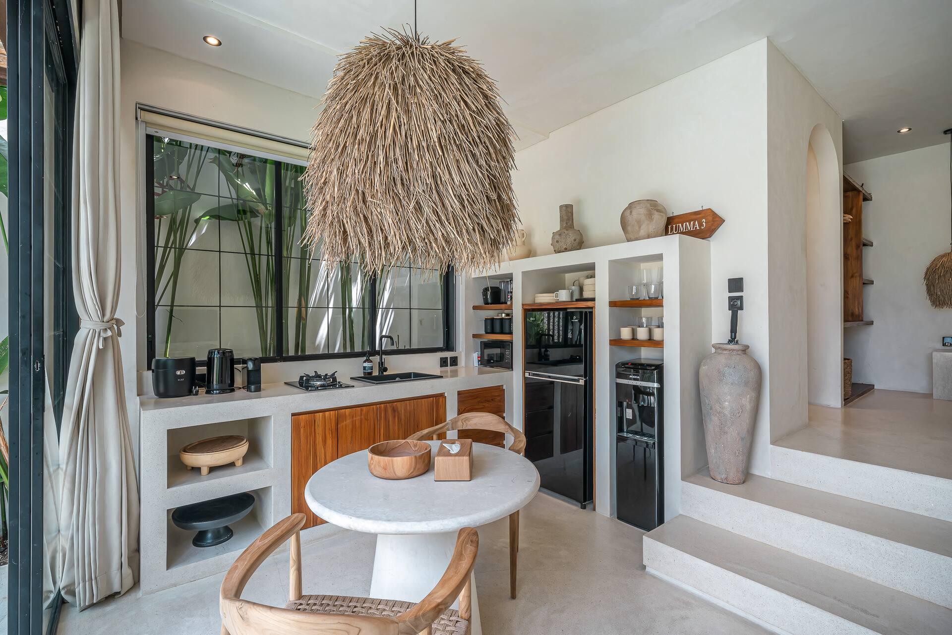 Kitchen bench in white render and timber with a wine cooler, beside the dining table