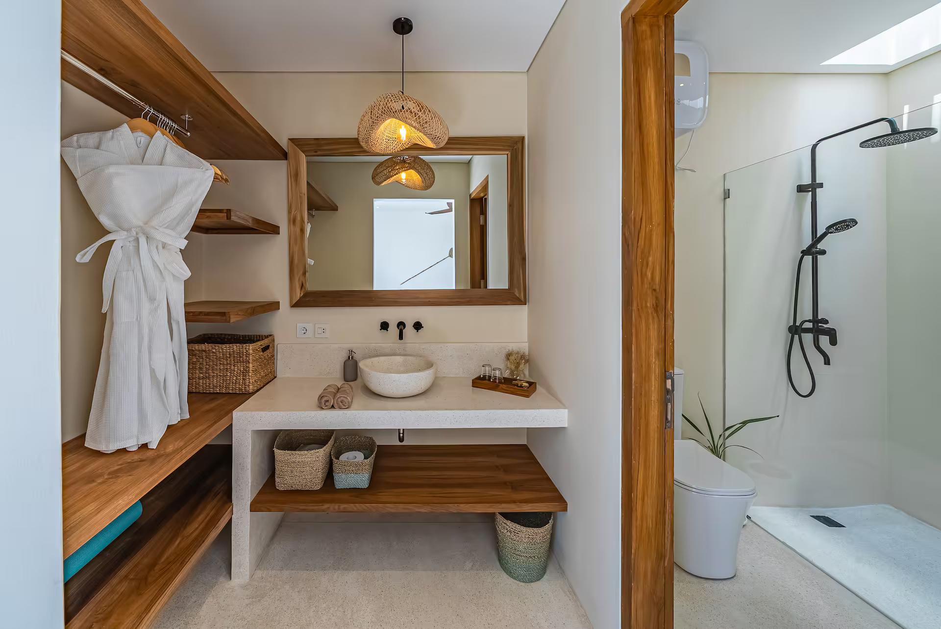 White bathroom with a stone vessel basin, timber shelving and a black rain shower