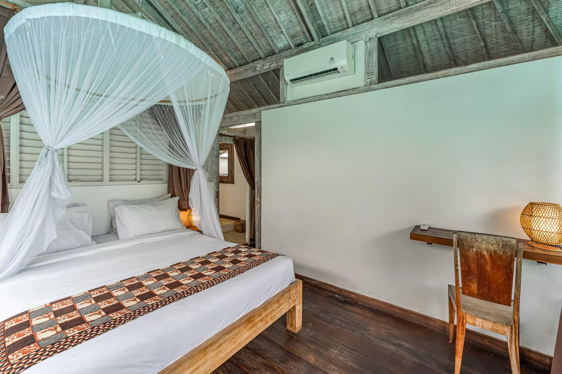 Second bedroom with a timber four-poster, writing desk and dark timber floor