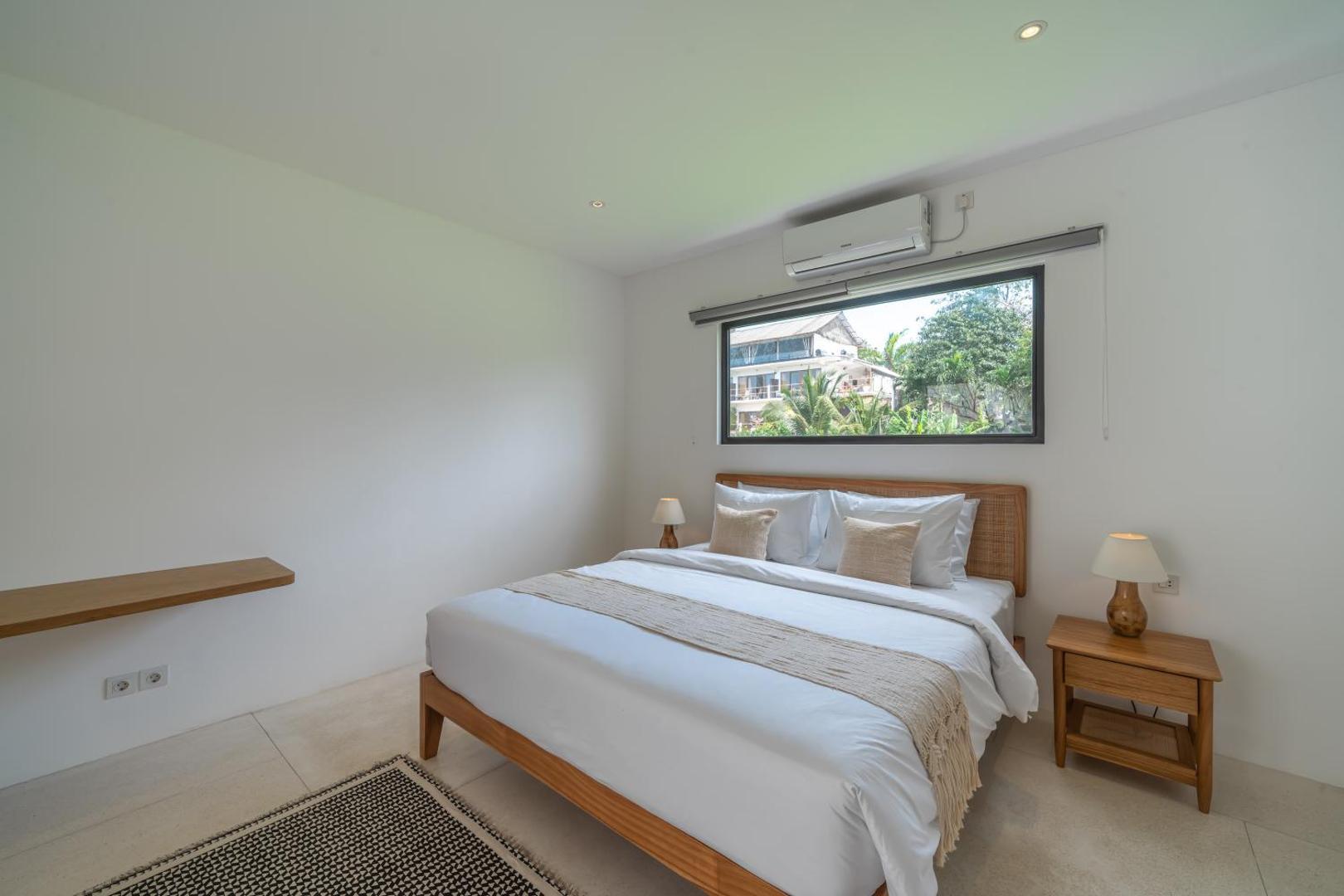Second king bedroom with a long window onto the garden and a striped rug
