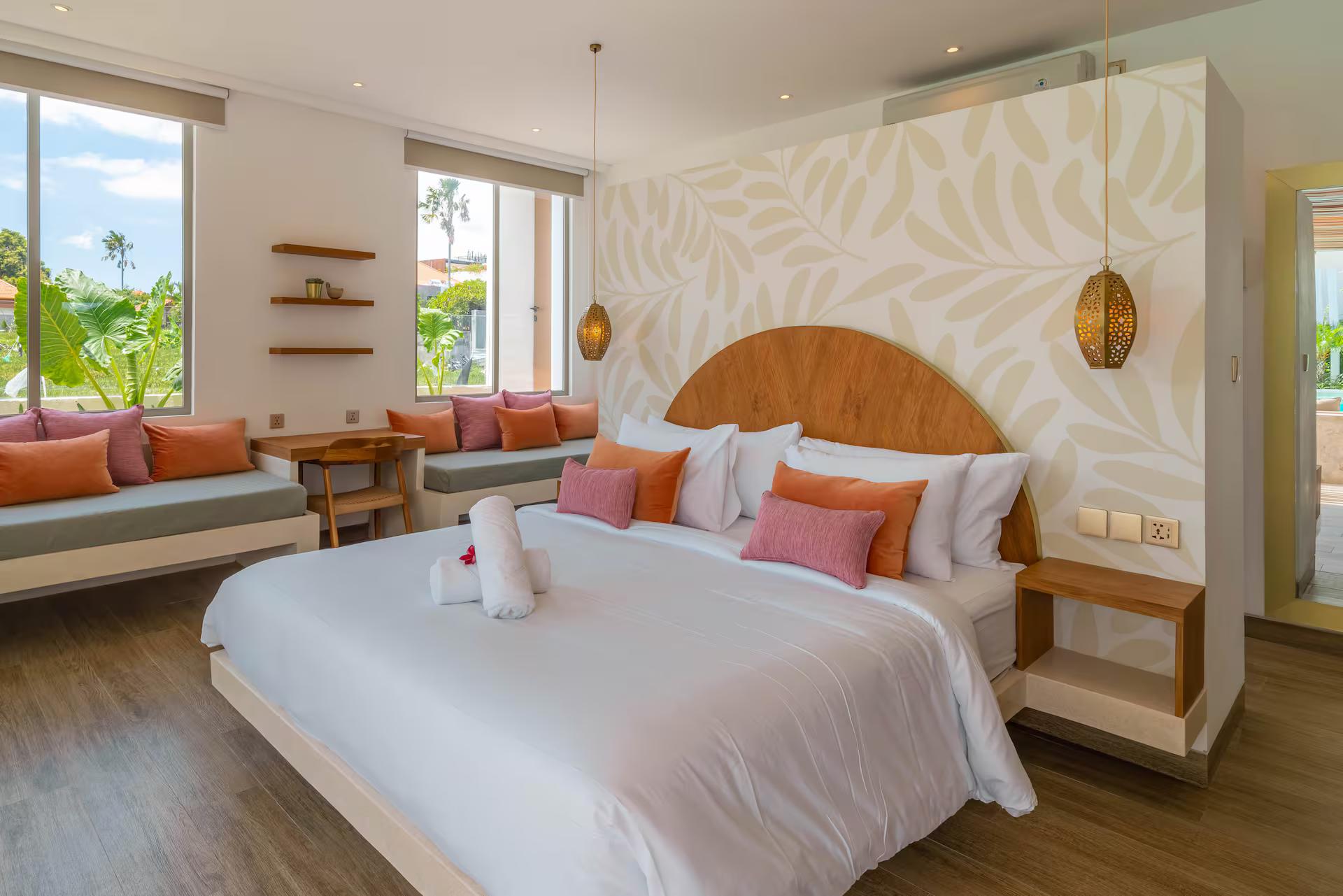 Bedroom with an arched timber headboard, leaf-print wallpaper and a built-in window bench