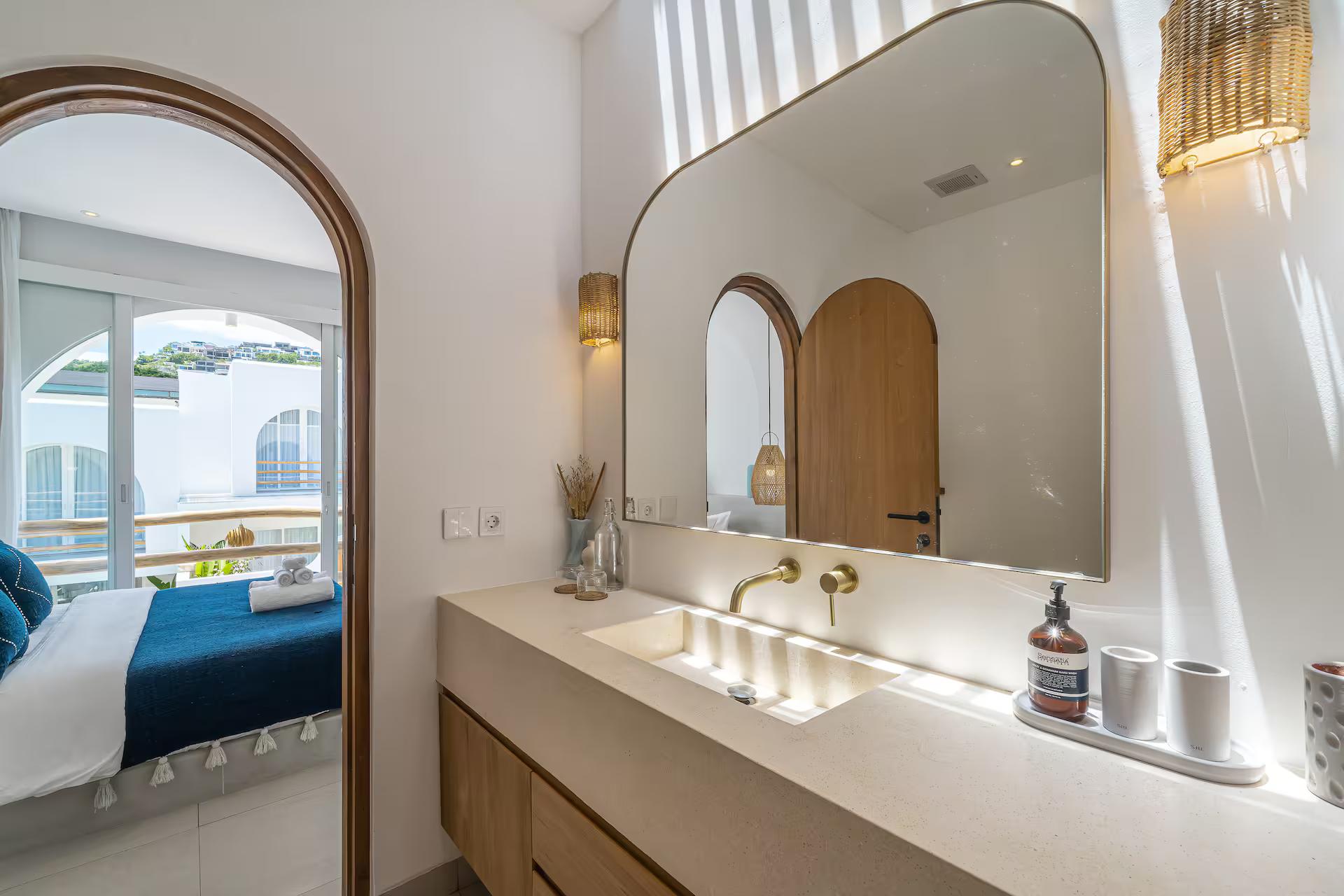 En-suite vanity at Villa Solaia in microcement, with brass taps and an arched mirror