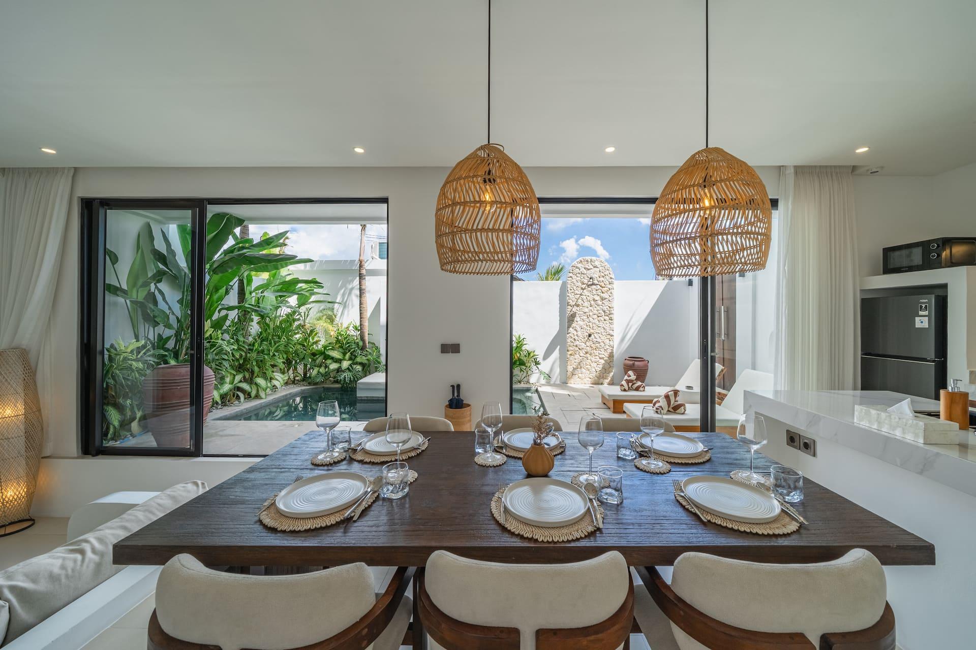 The dark timber dining table set for eight beside folding doors that open onto the pool deck